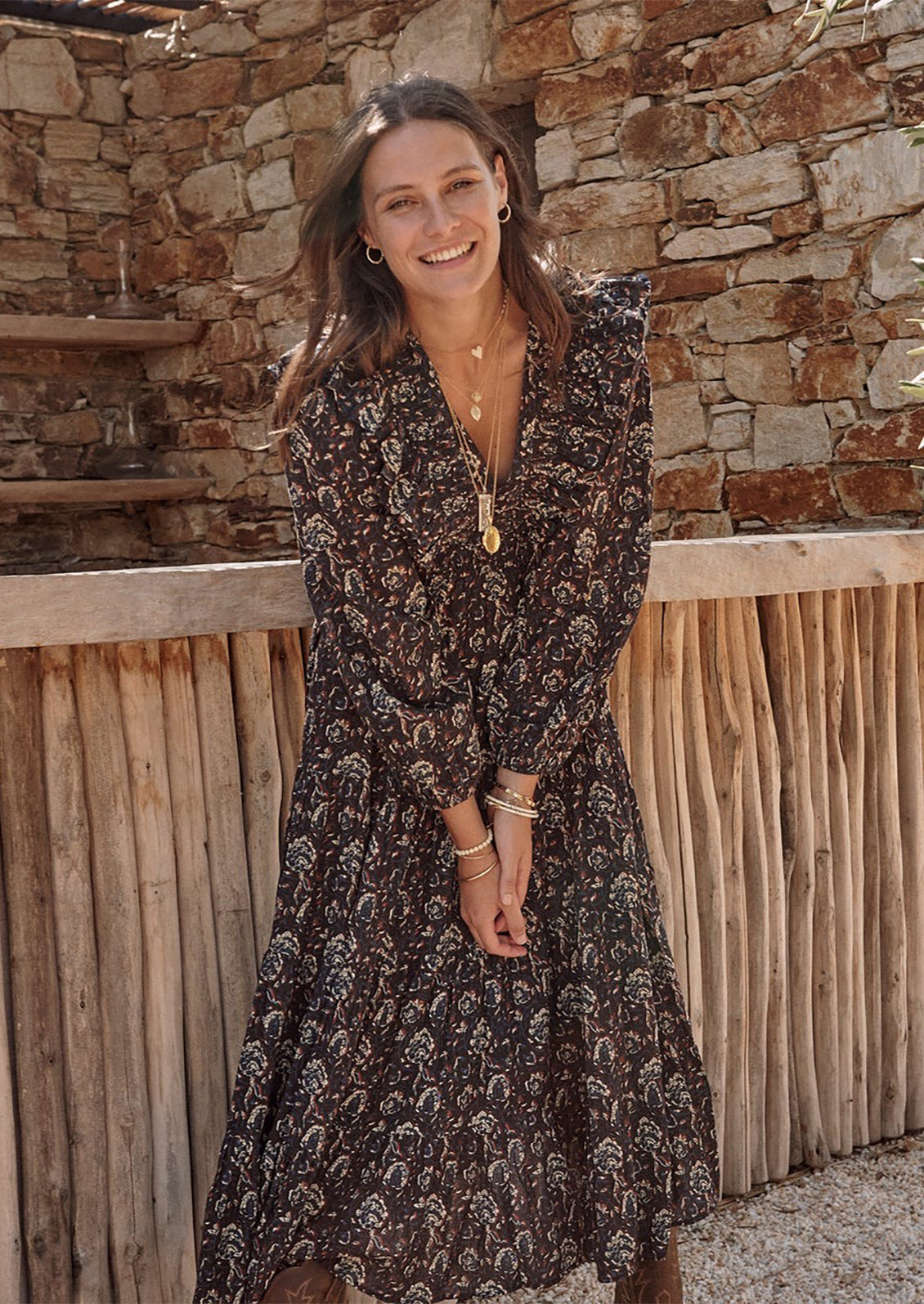 A long sleeve maxi dress with ruffled v-neck in black with blue, white and rust block print pattern.