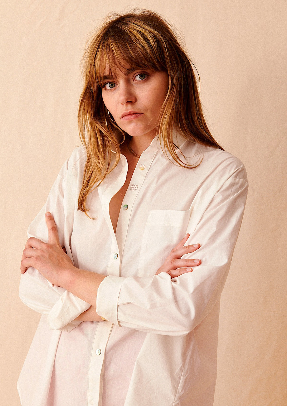 A woman wearing an oversized white cotton shirt.