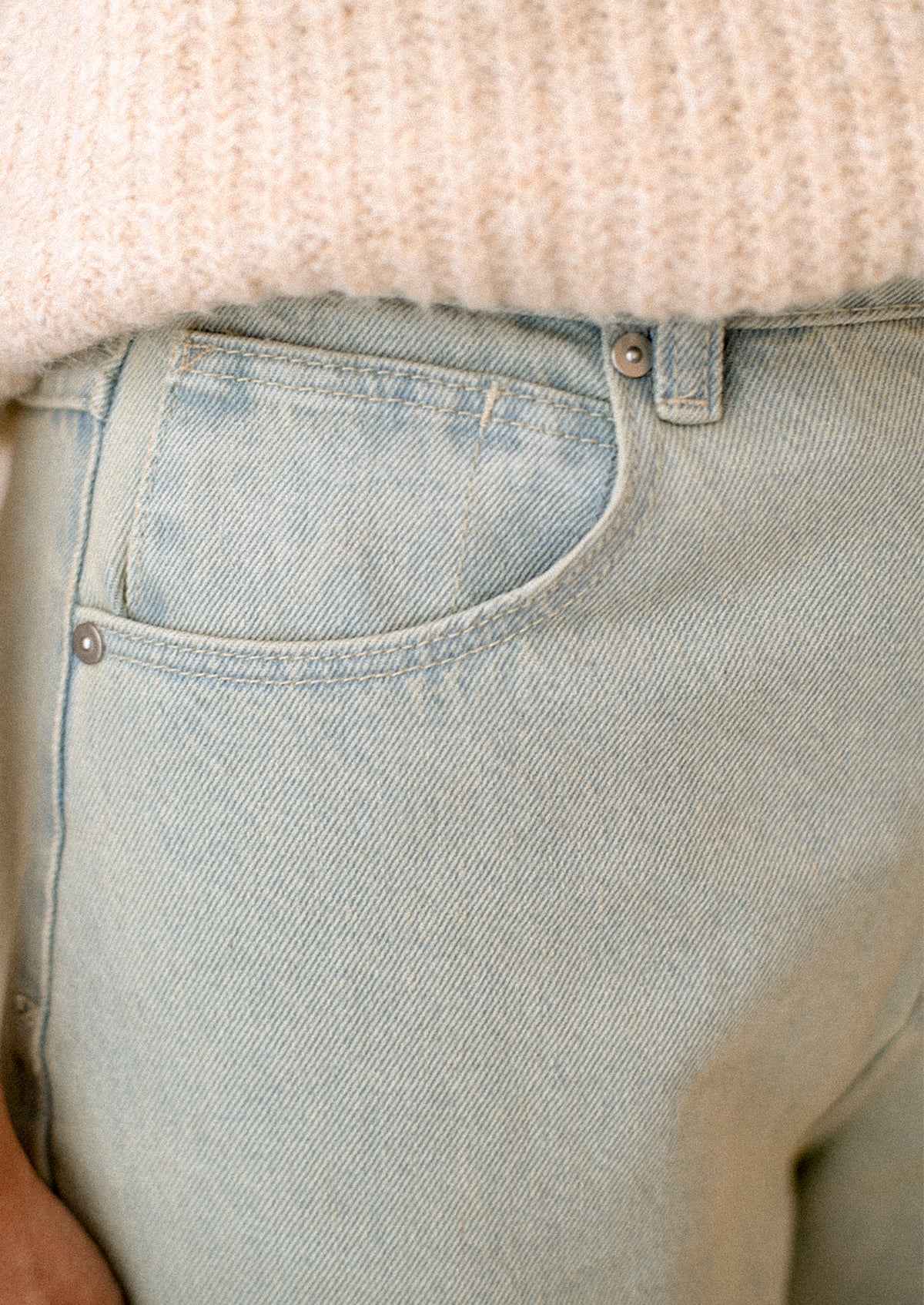 A woman wearing a pair of jeans in subtle green tinted light blue wash.