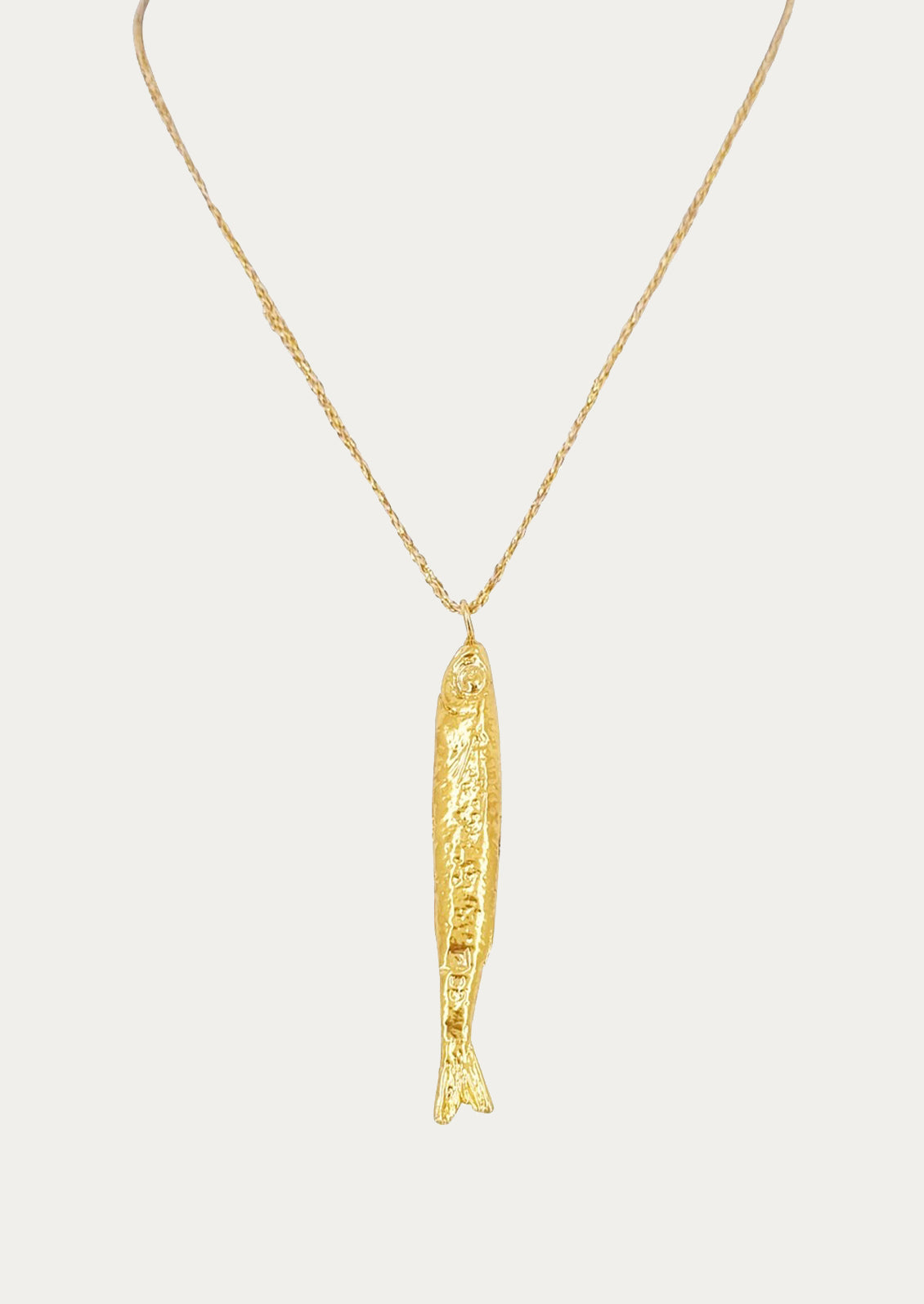A necklace on gold string with single fish charm.
