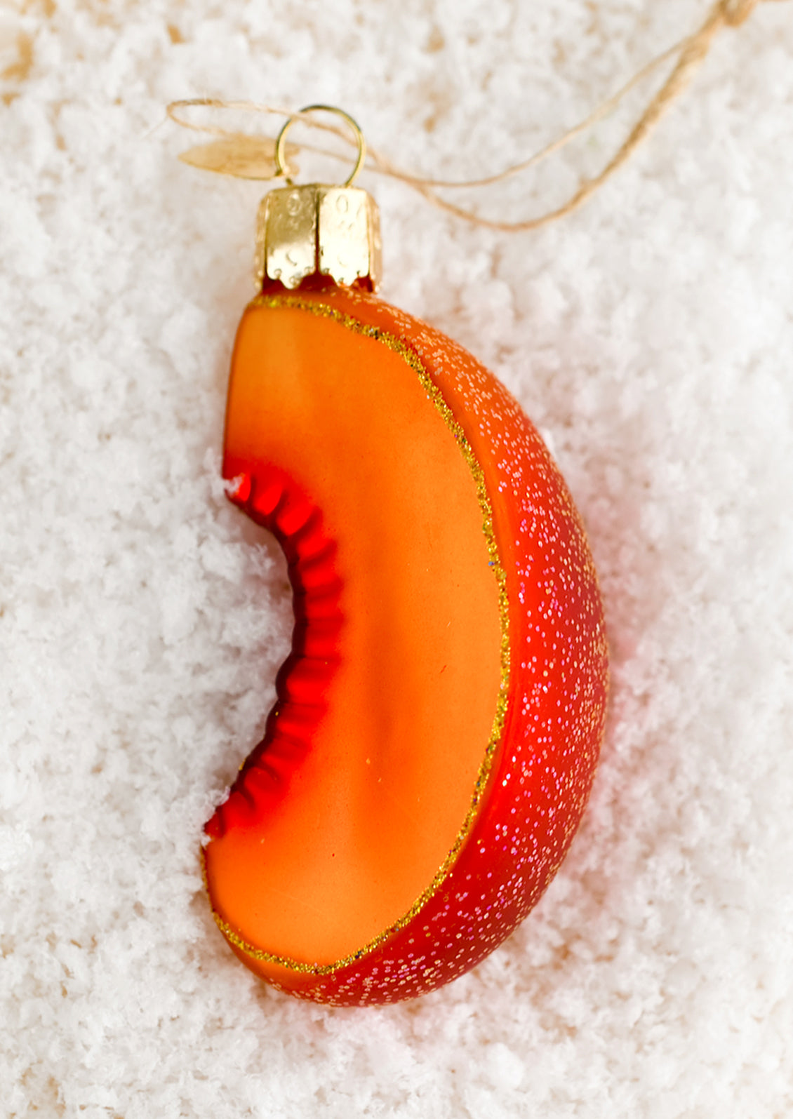 A glass ornament in the shape of a sliced peach.