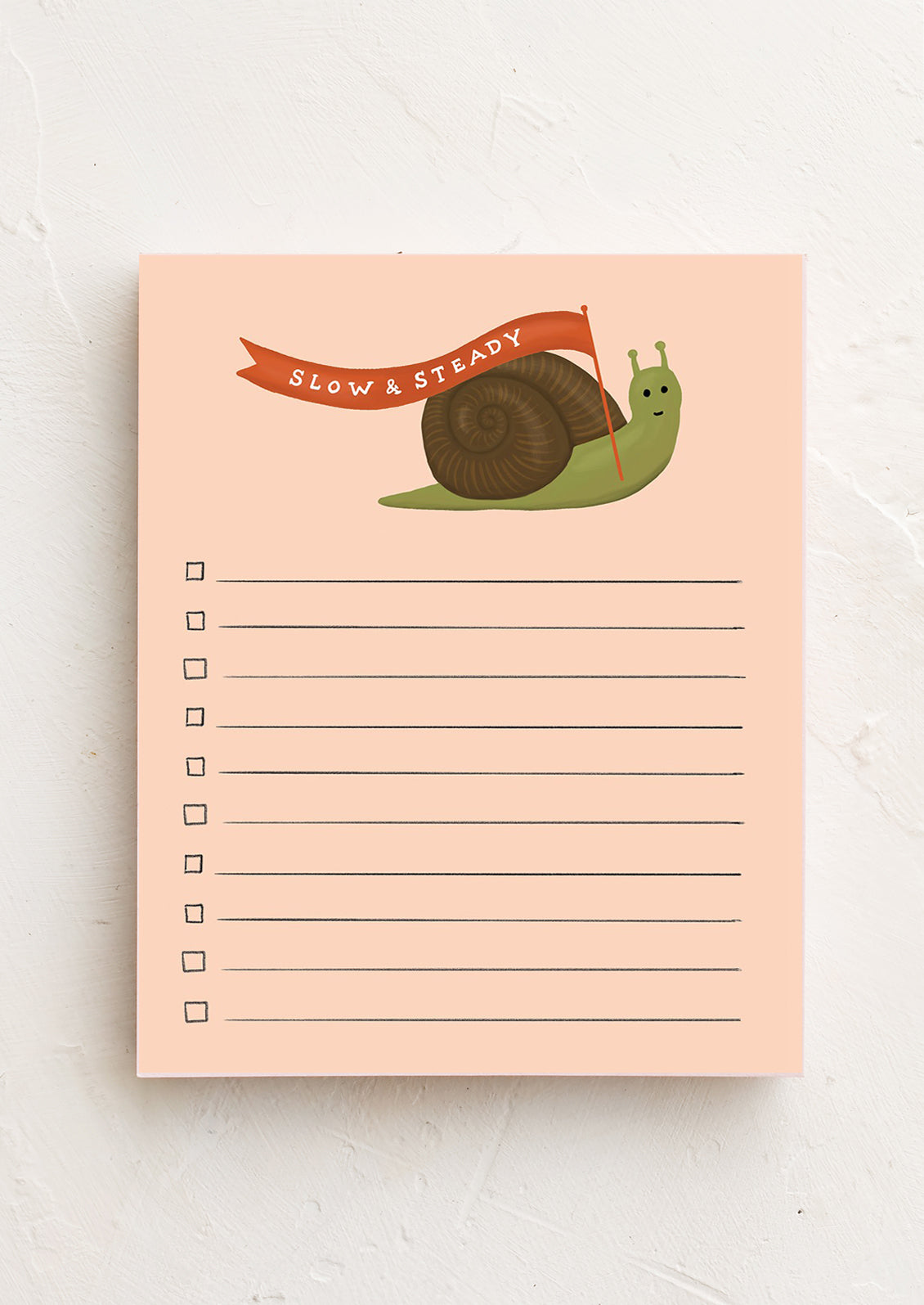 A notepad with a peach color background featuring an illustration of a snail at the top and lined space for writing.