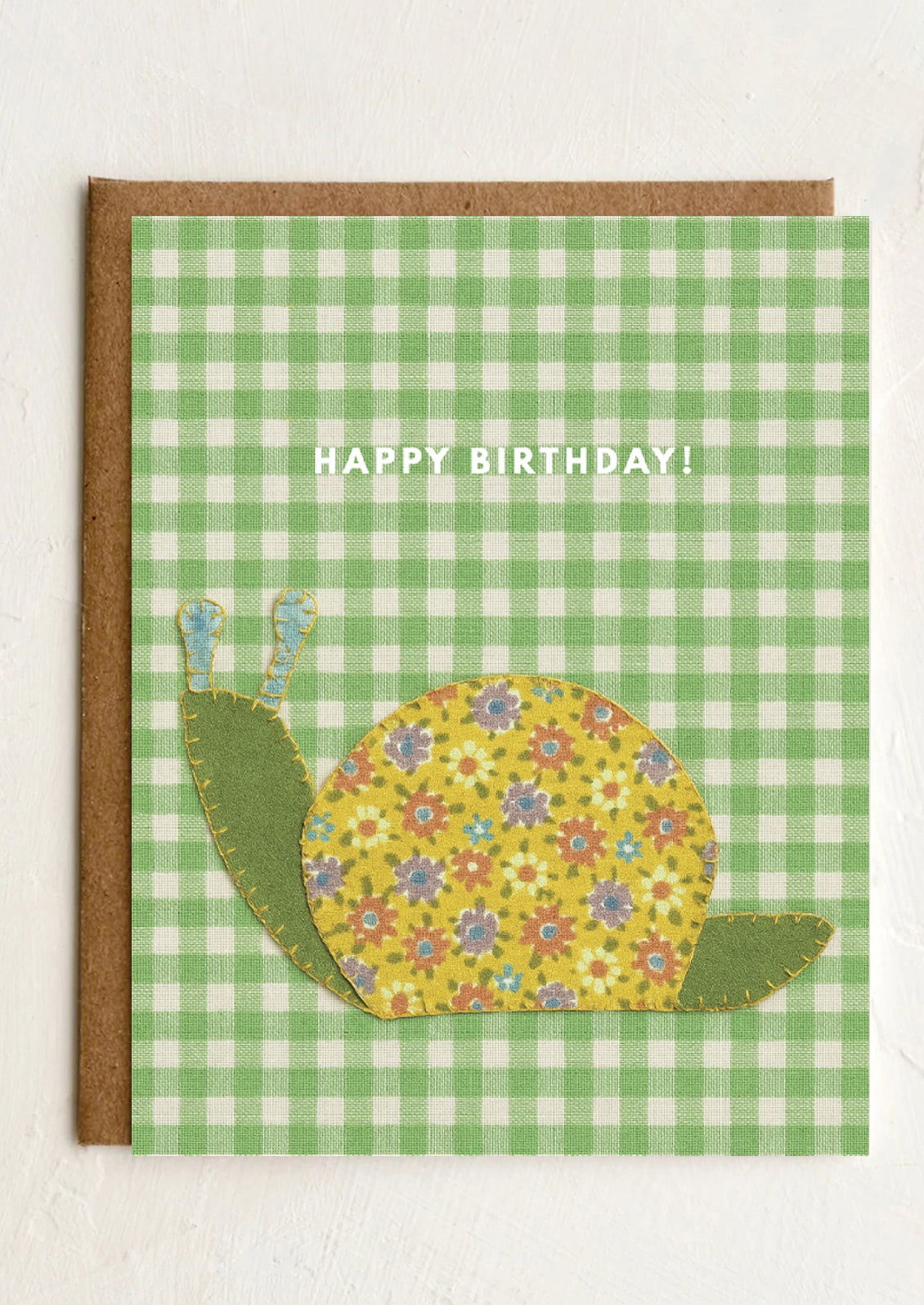 Birthday card with a floral snail design on a green checkered background