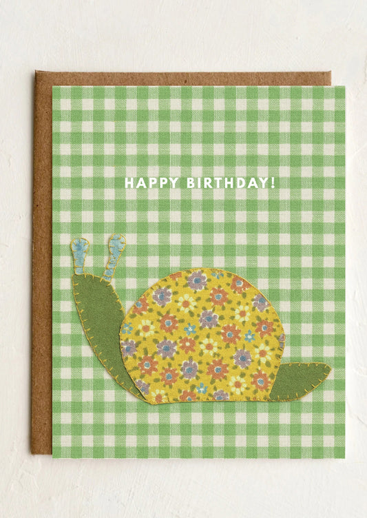 Birthday card with a floral snail design on a green checkered background
