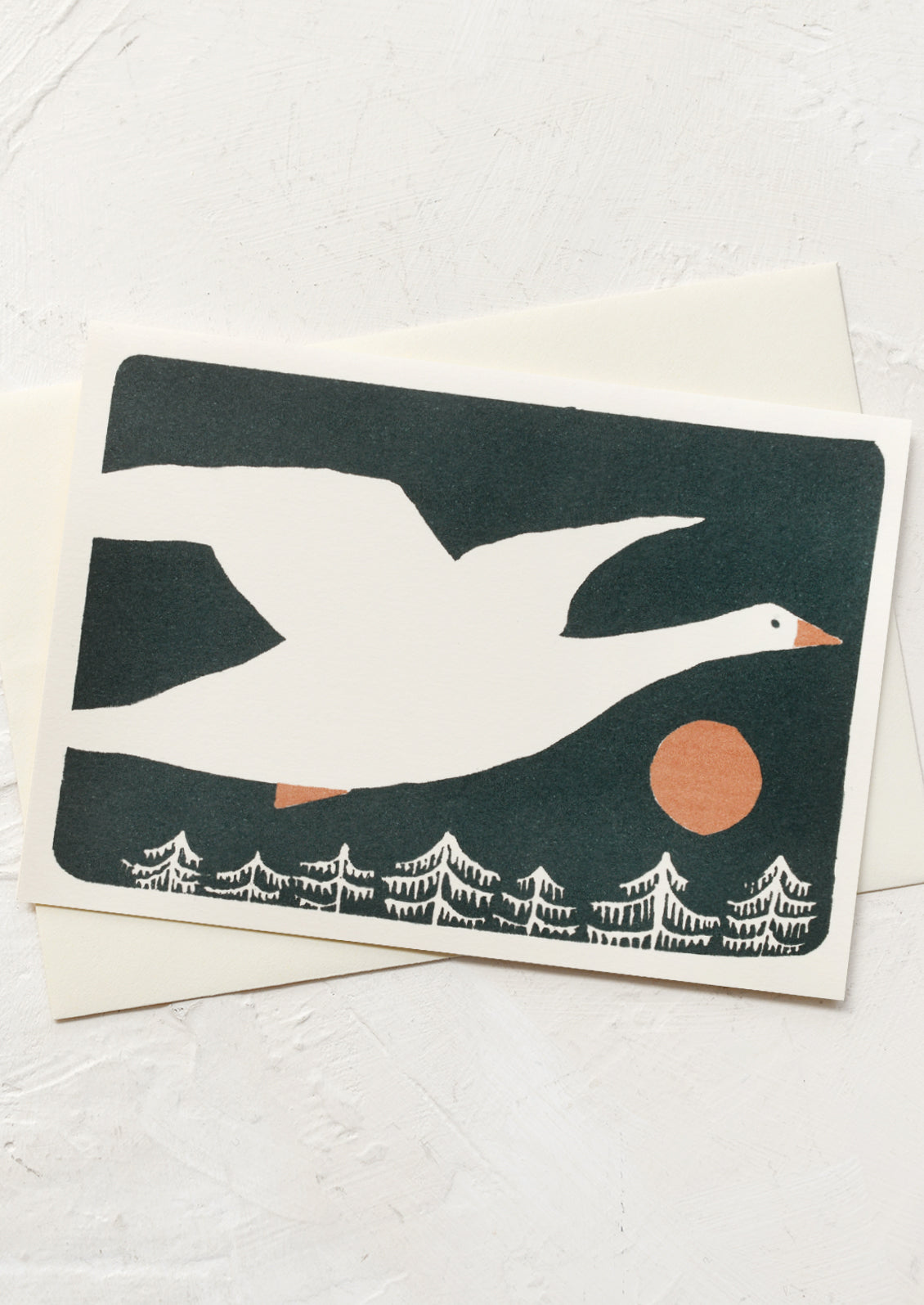 An illustrated card with duck flying over pine trees.