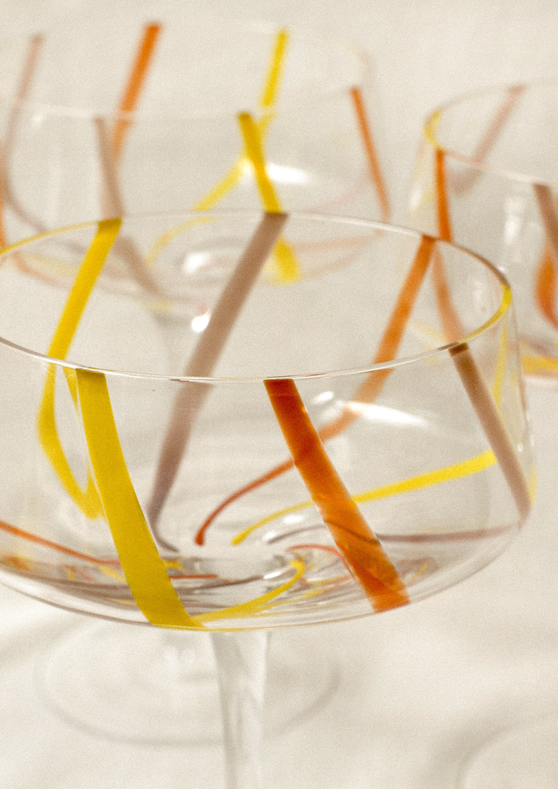Clear coupe glass with colorful stripes.