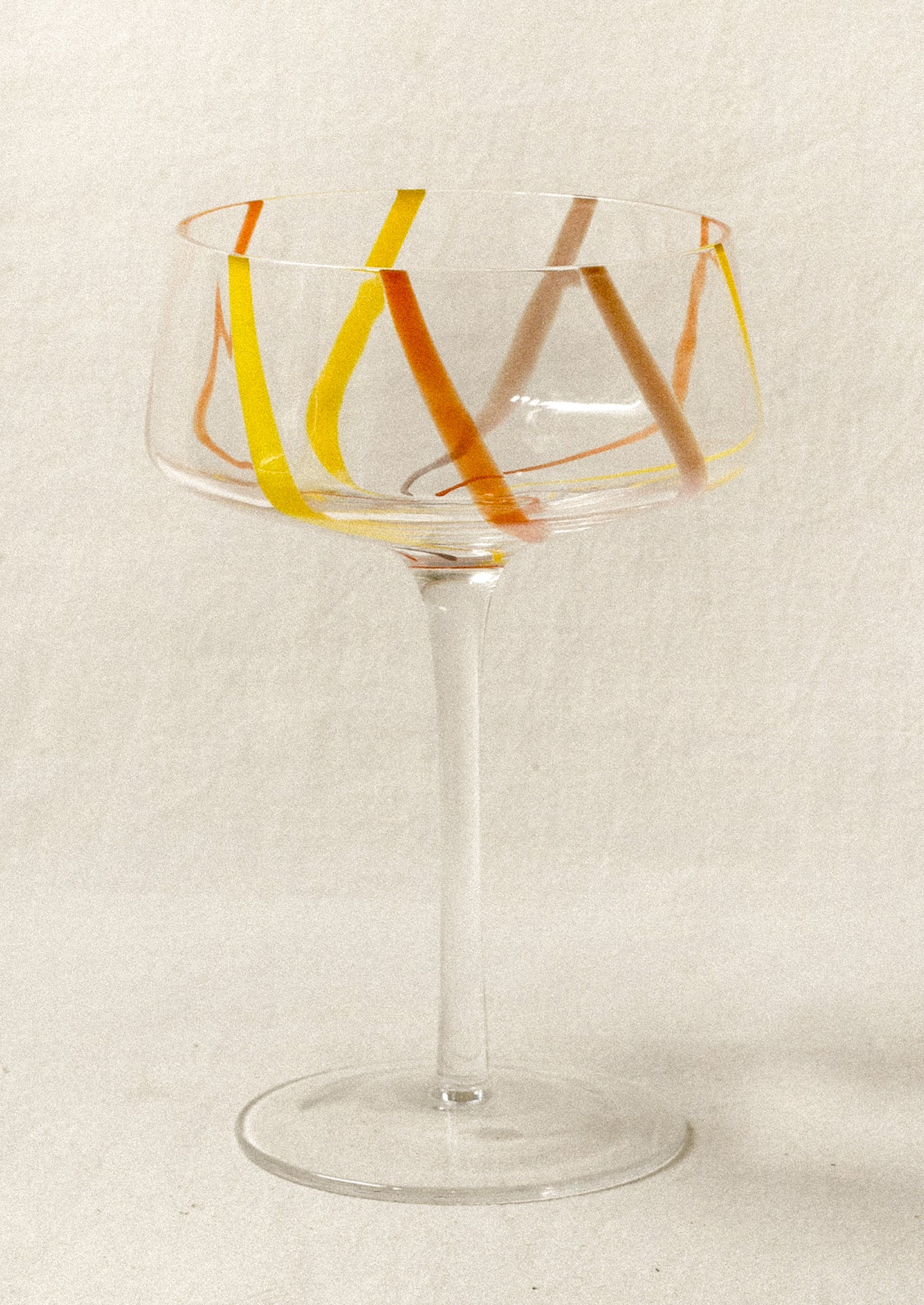 Clear coupe glass with colorful stripes.