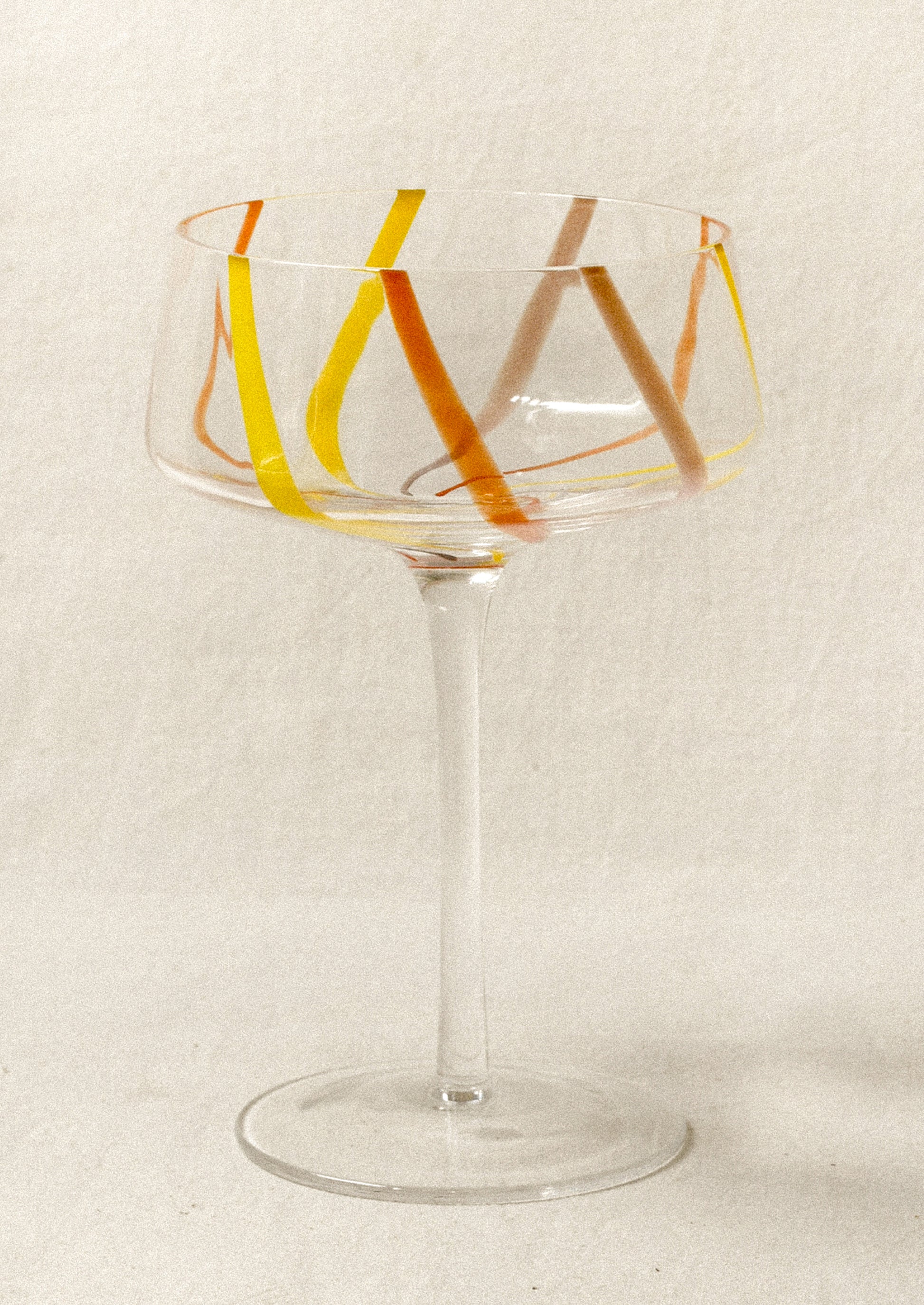 Clear coupe glass with colorful stripes.