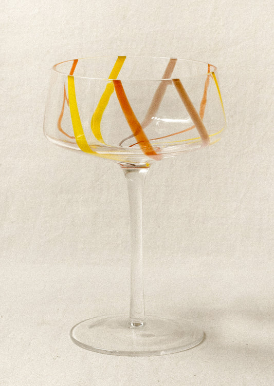 Clear coupe glass with colorful stripes.