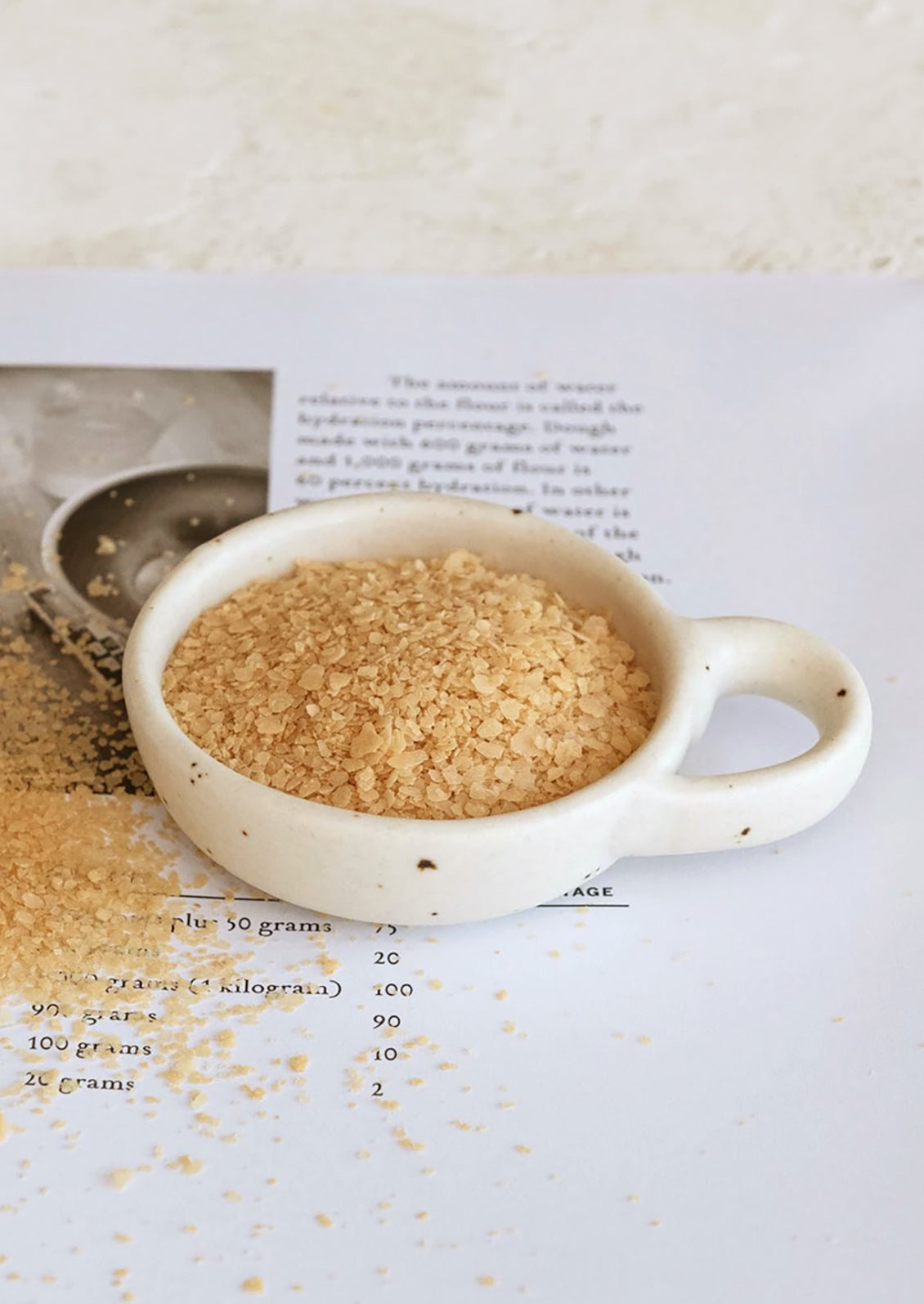 A small ceramic pinch bowl in speckled white ceramic with decorative handle.