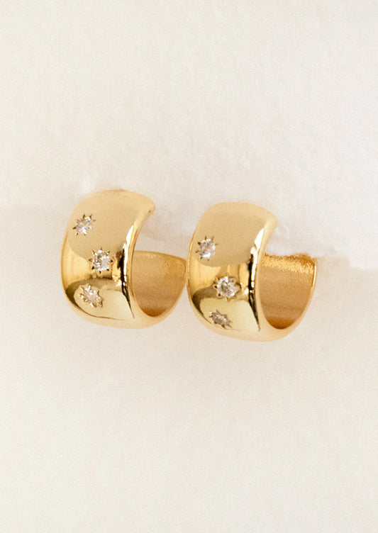 A pair of chunky gold hoops with starry gems.