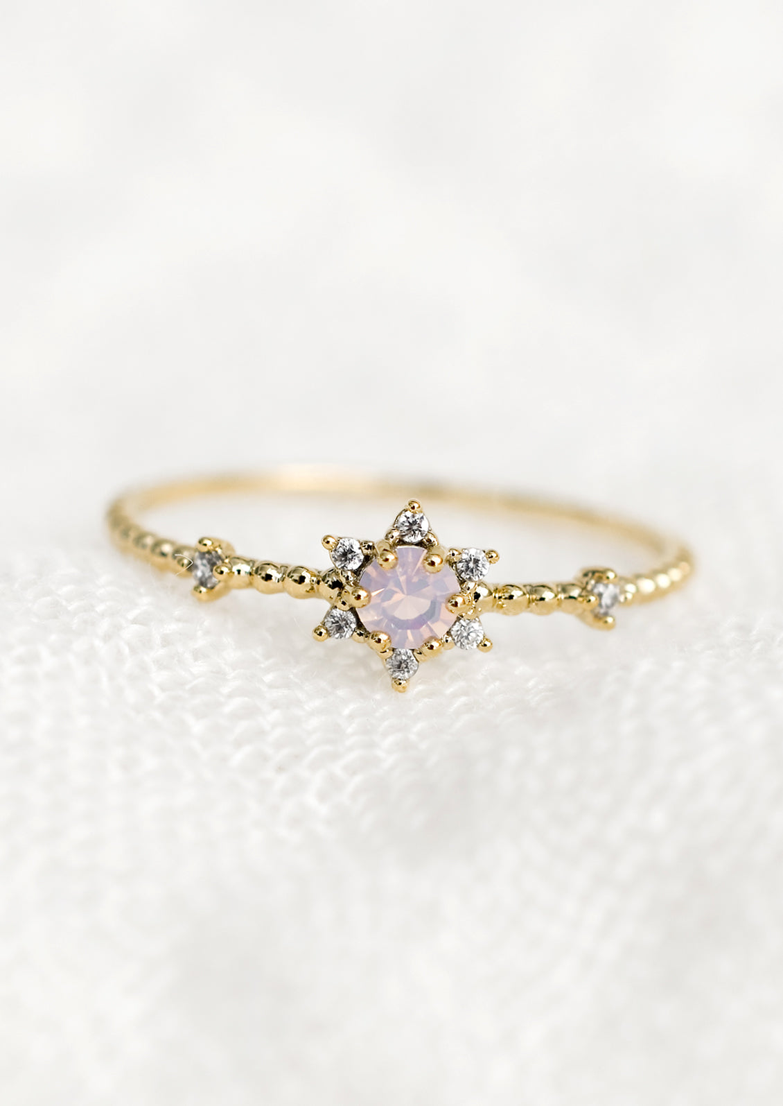 A gold ring with star-shaped setting in opal and clear crystal.