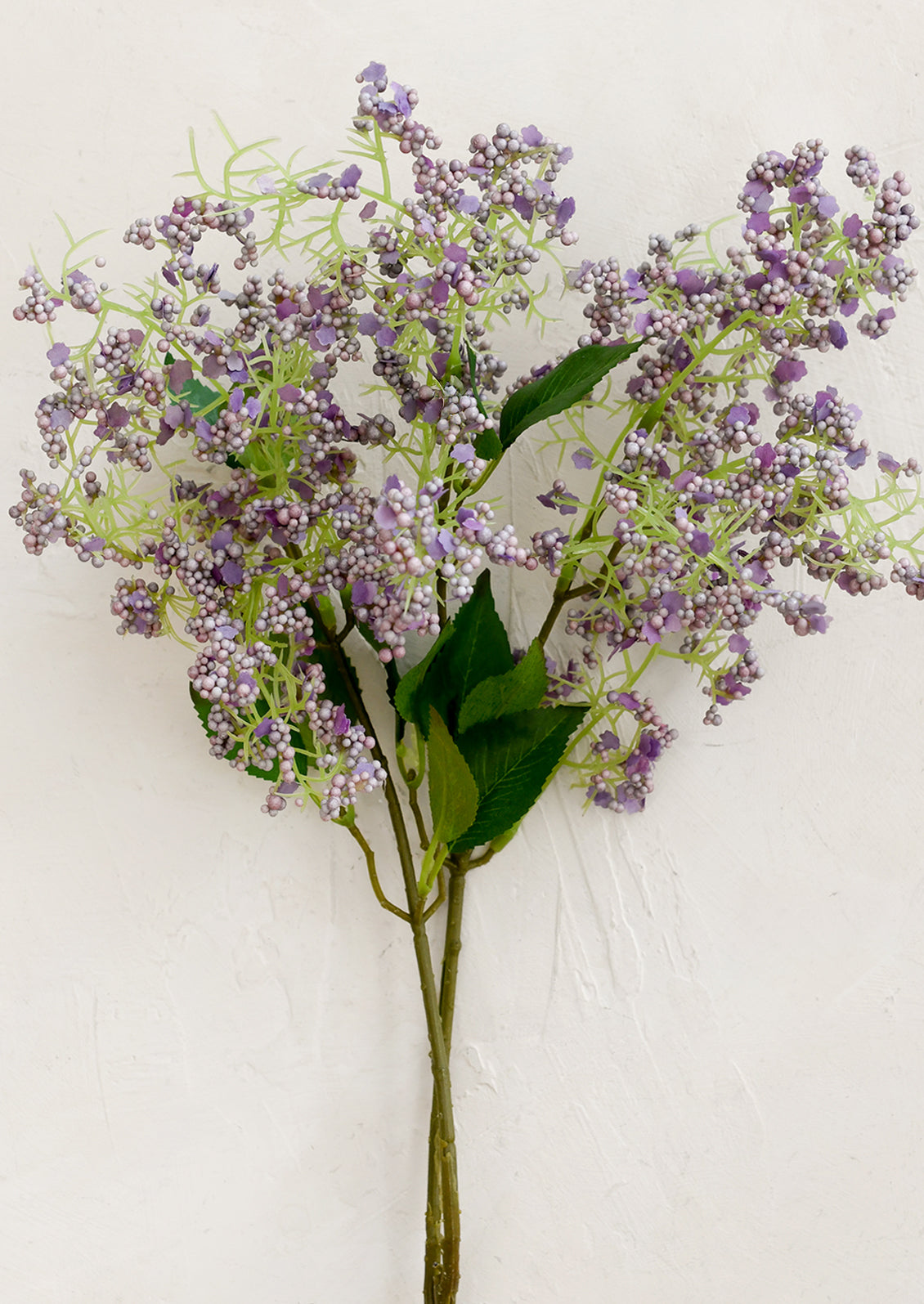 A faux flower stem depicting sticky laurel in light purple.