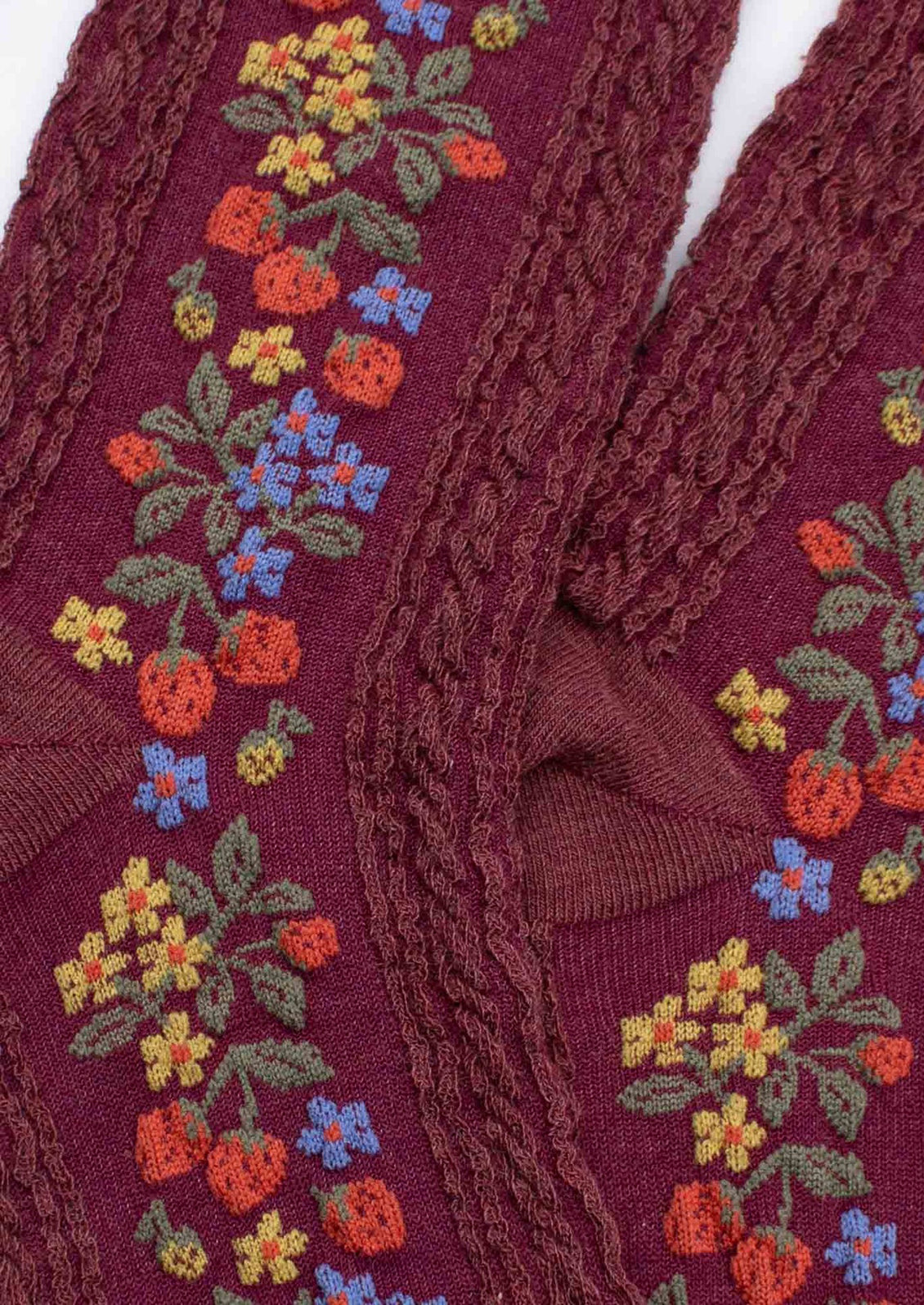 A pair of burgundy colored socks with strawberry print.