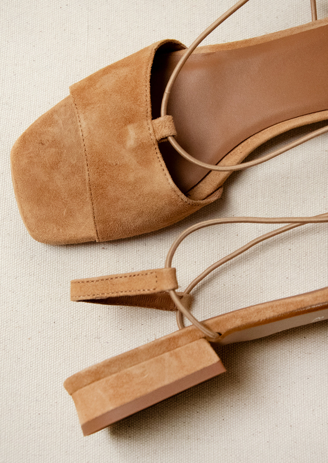 A pair of suede slingback heeled sandals in a camel color.