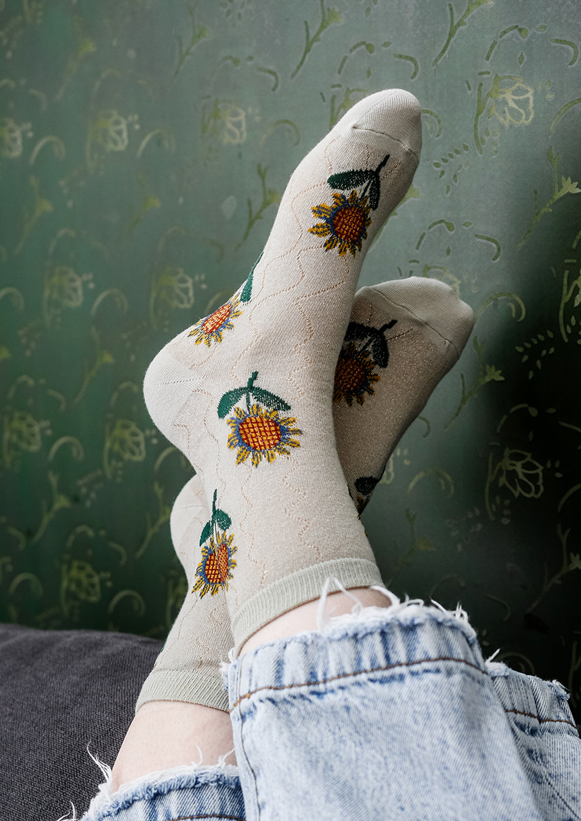 A pair of seafoam colored socks with sunflower pattern.