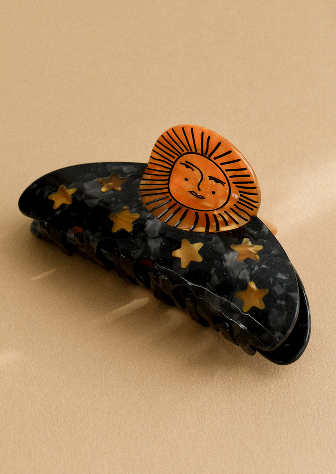 A black hair claw with copper sun and star pattern.