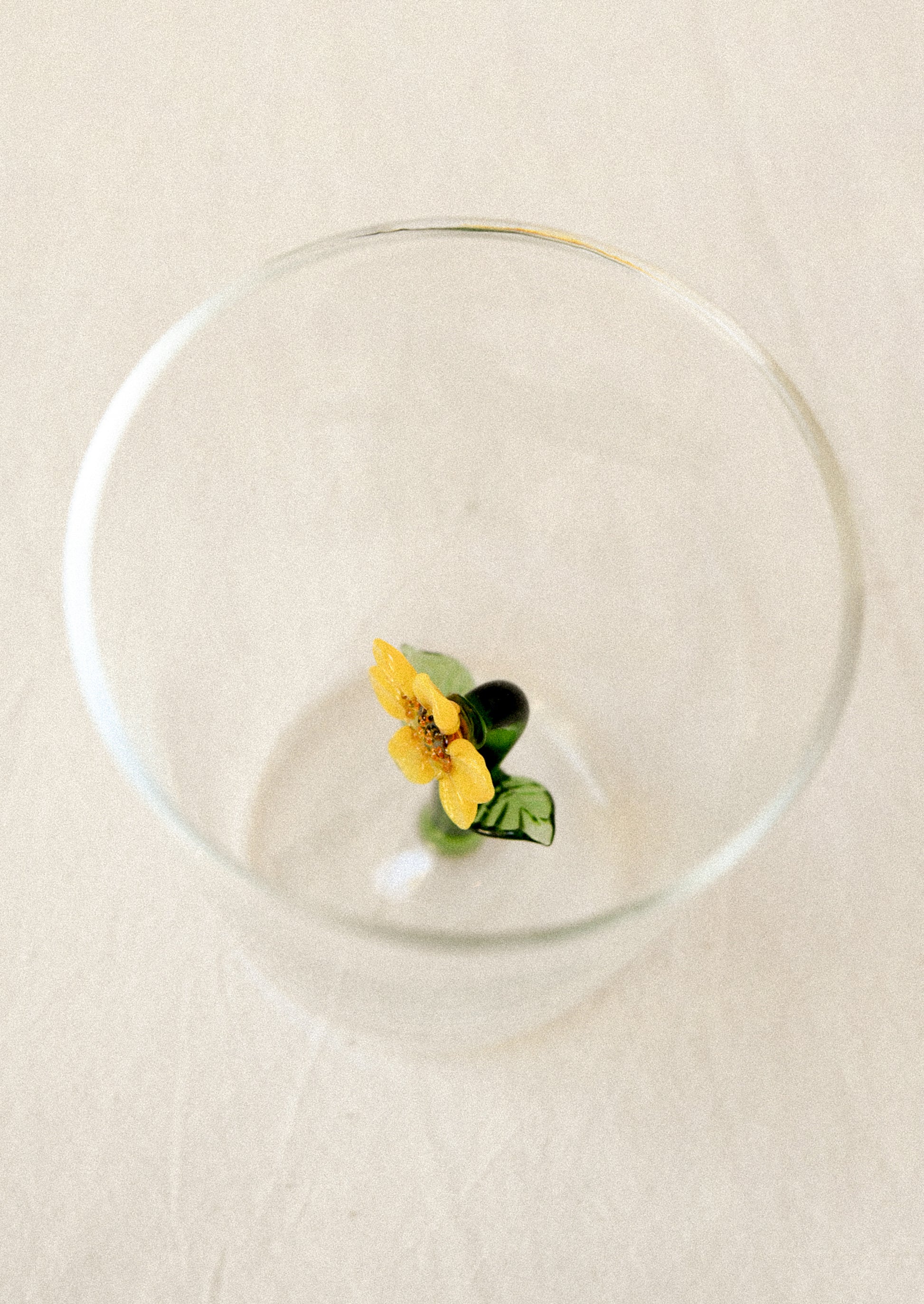 Clear drinking glass with a yellow sunflower charm inside glass.