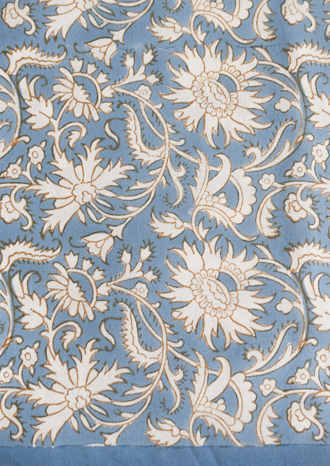 A block print tablecloth in sky blue with white and brown floral print.