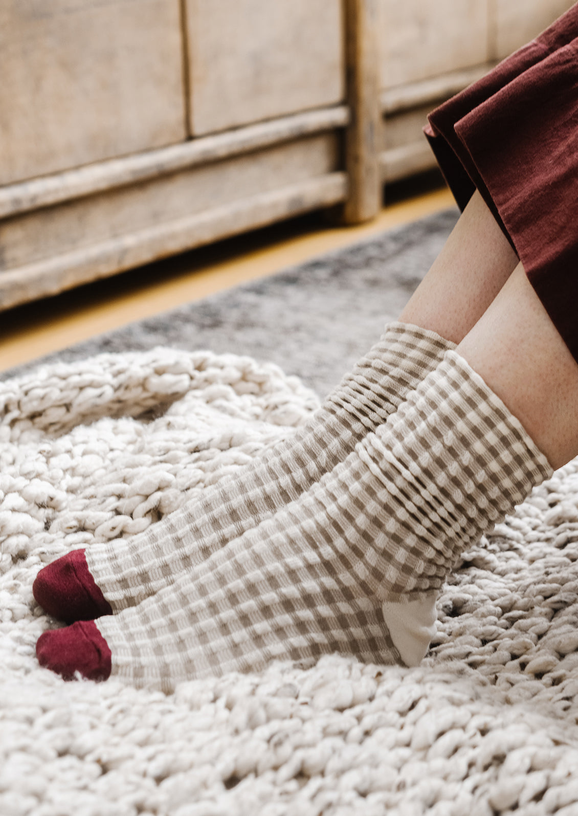 A pair of socks in cream gingham with burgundy cap toe.
