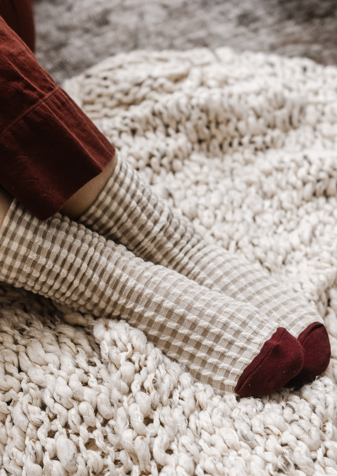 A pair of socks in cream gingham with burgundy cap toe.