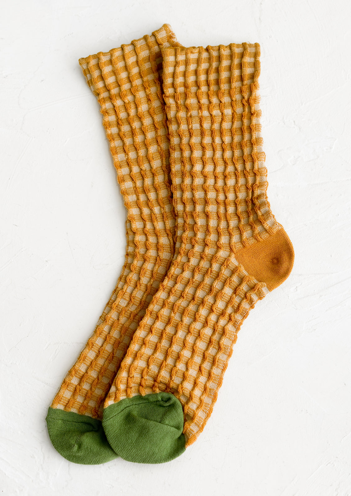 A pair of socks in mustard gingham with green cap toe.