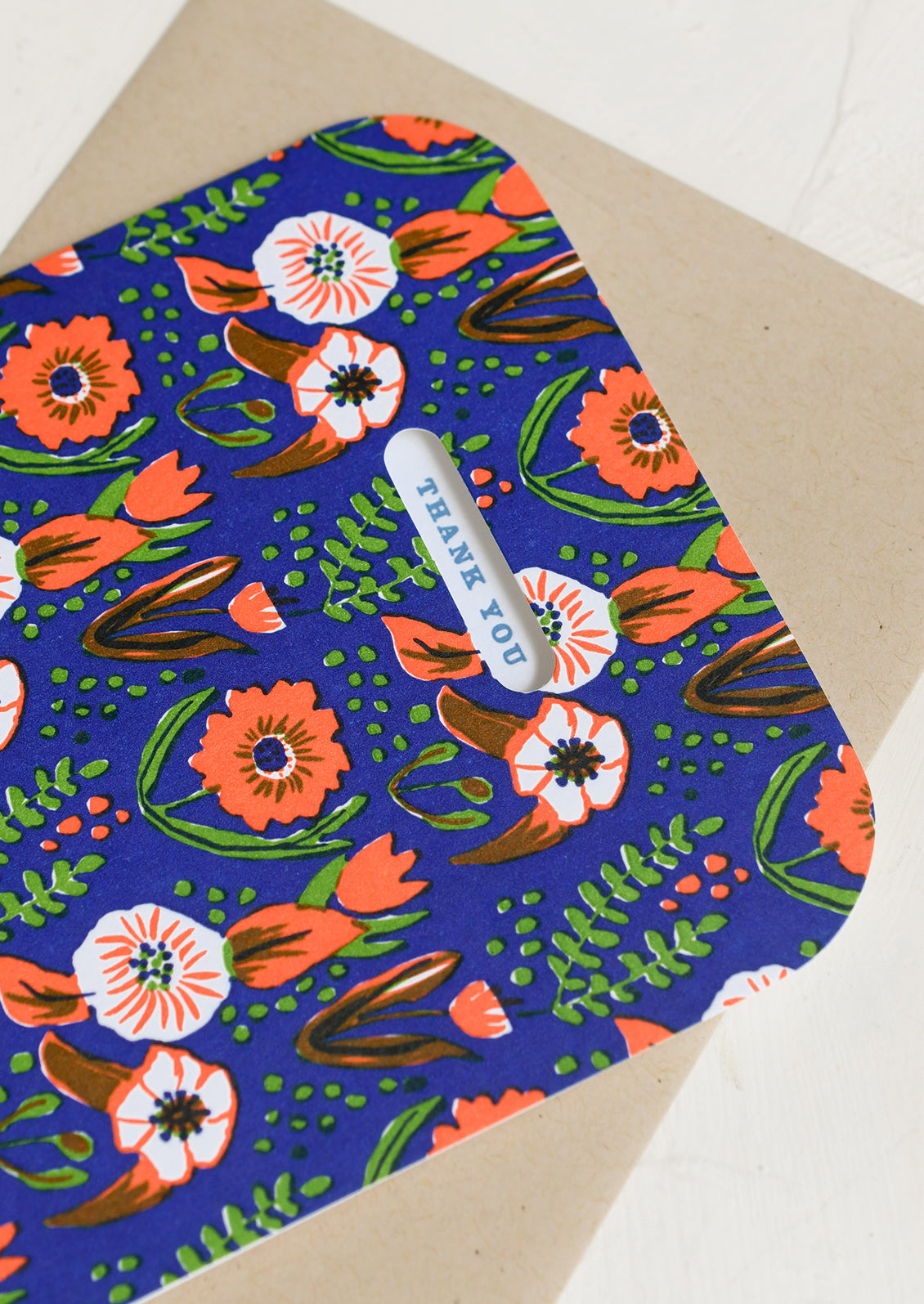 A dark blue and red floral print greeting card reading "Thank you".