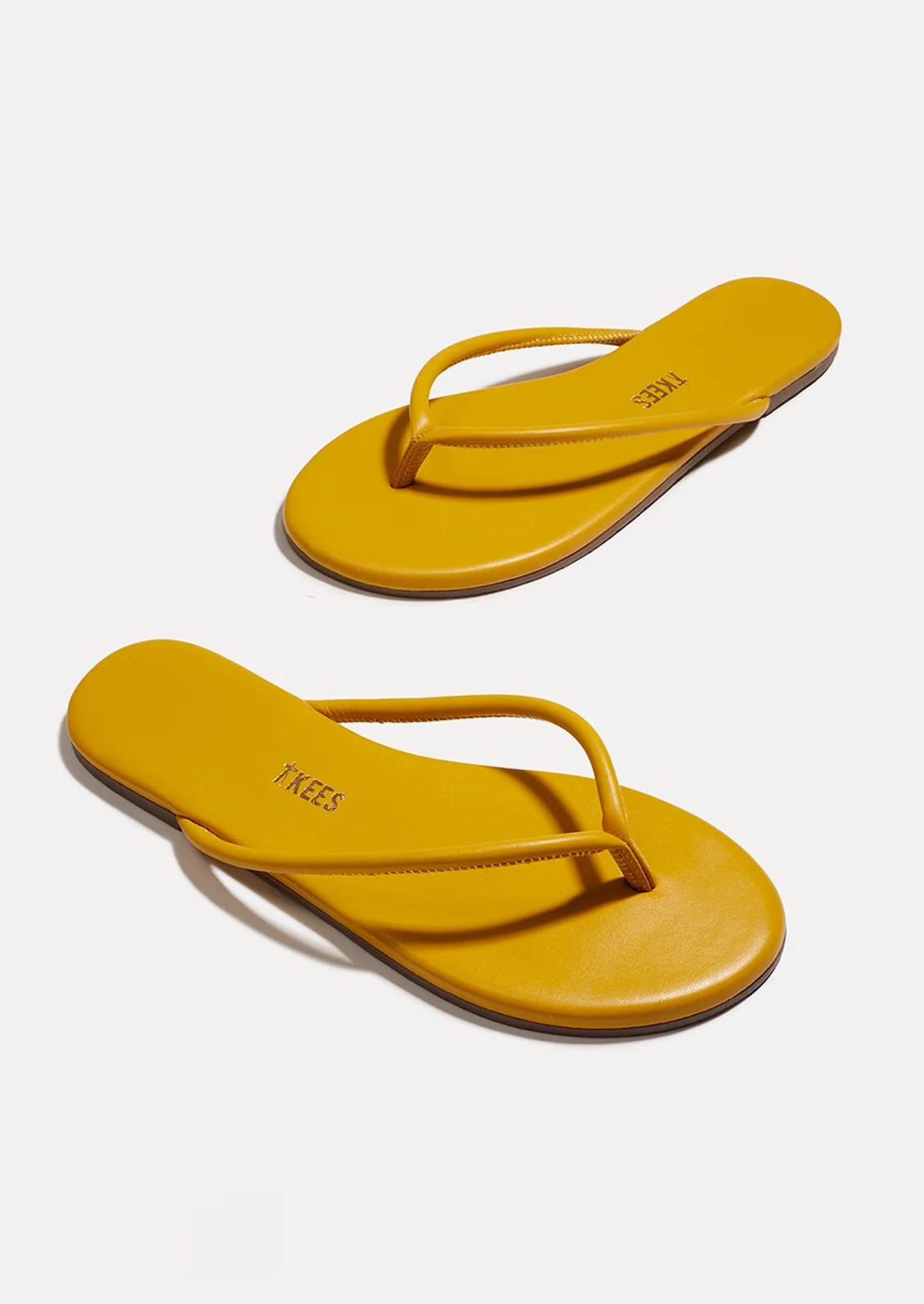 A pair of leather TKEES sandals with a tubular strap design in deep yellow.