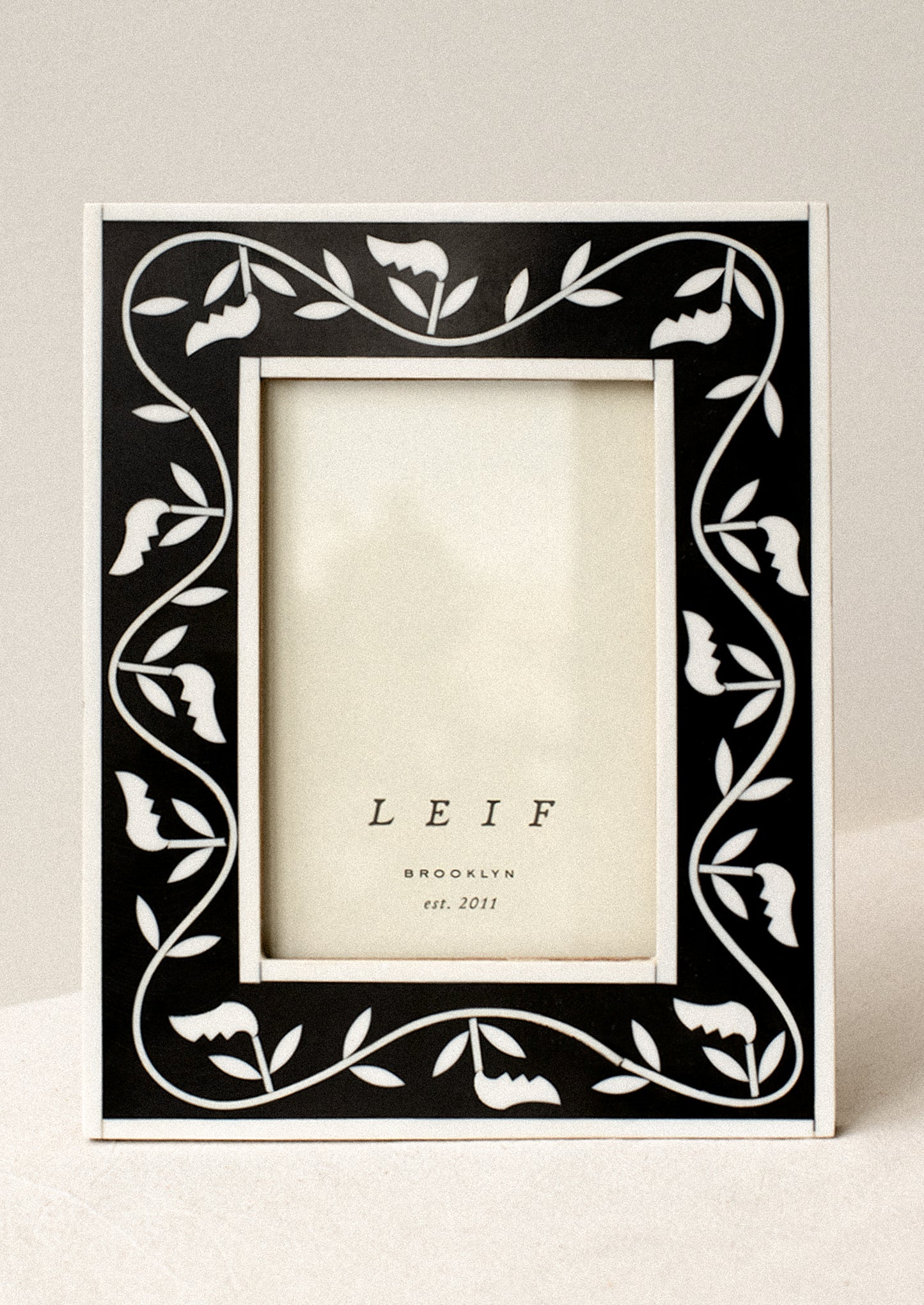 A black and white inlay frame with leaf pattern.