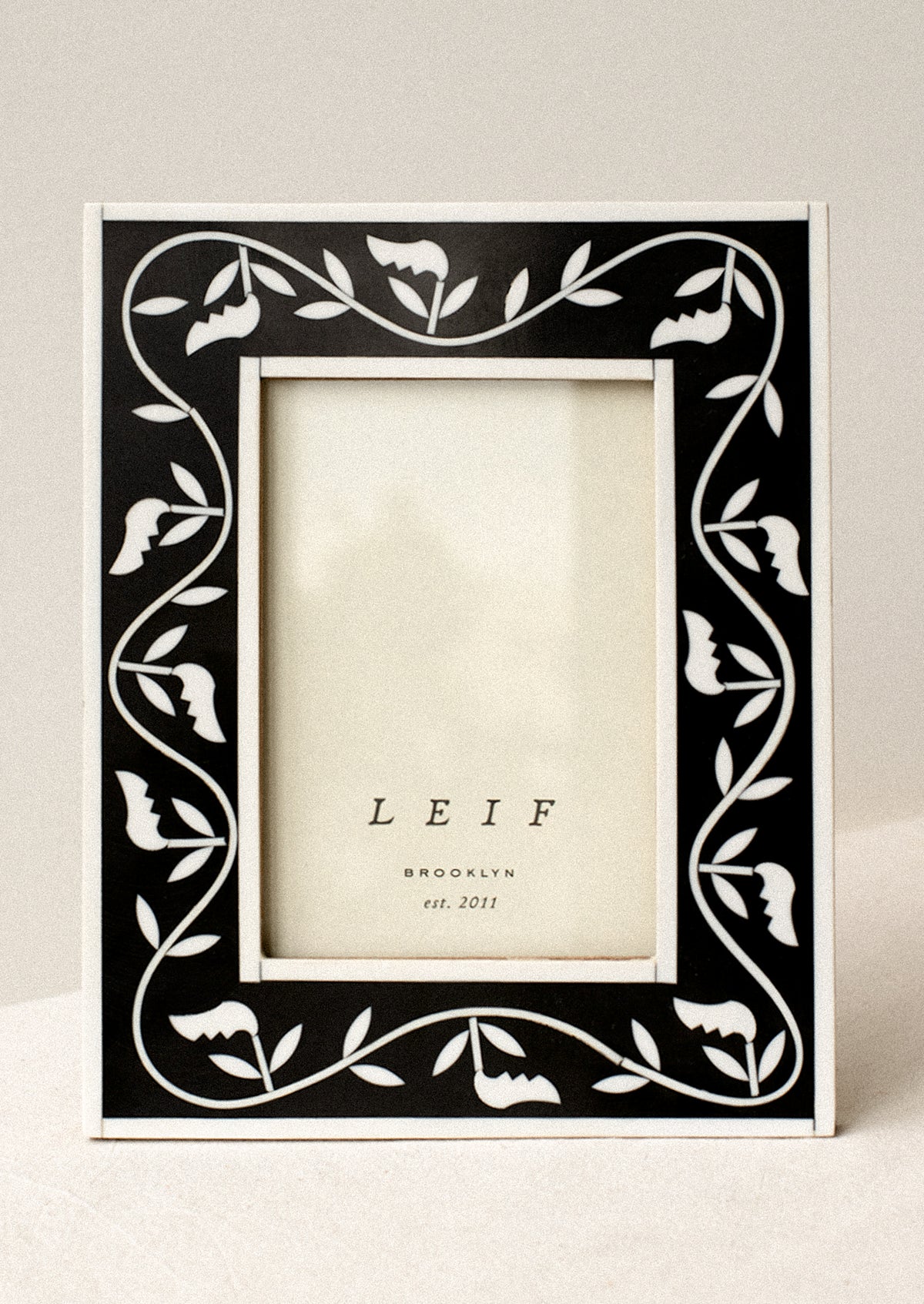A black and white inlay frame with leaf pattern.