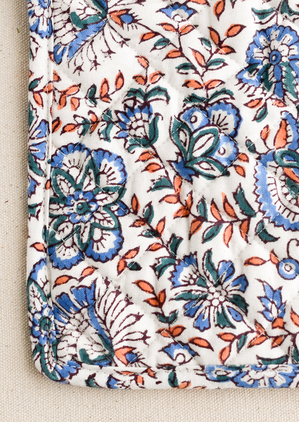 A quilted cotton pot holder in blue and pink block print.