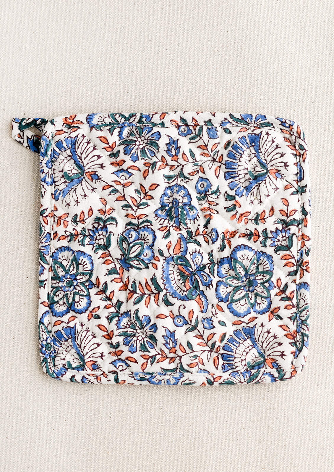 A quilted cotton pot holder in blue and pink block print.