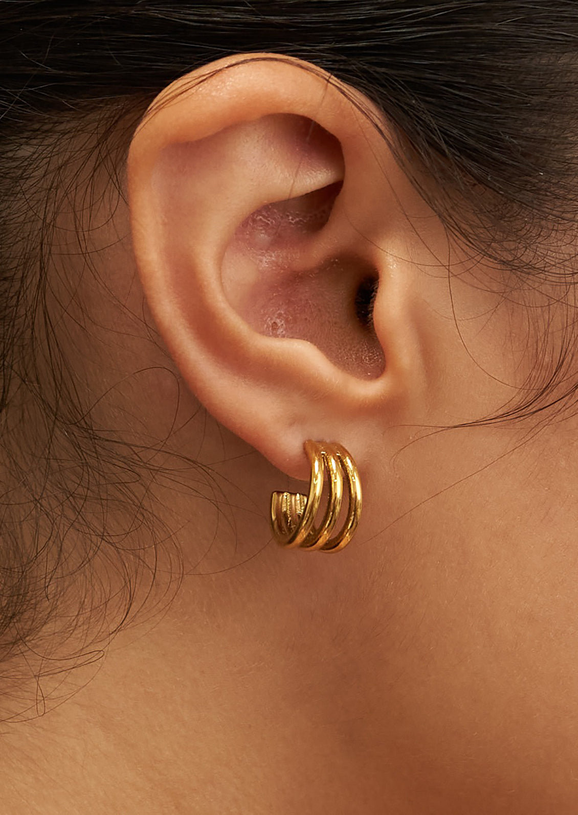 A pair of gold triple hoop earrings.