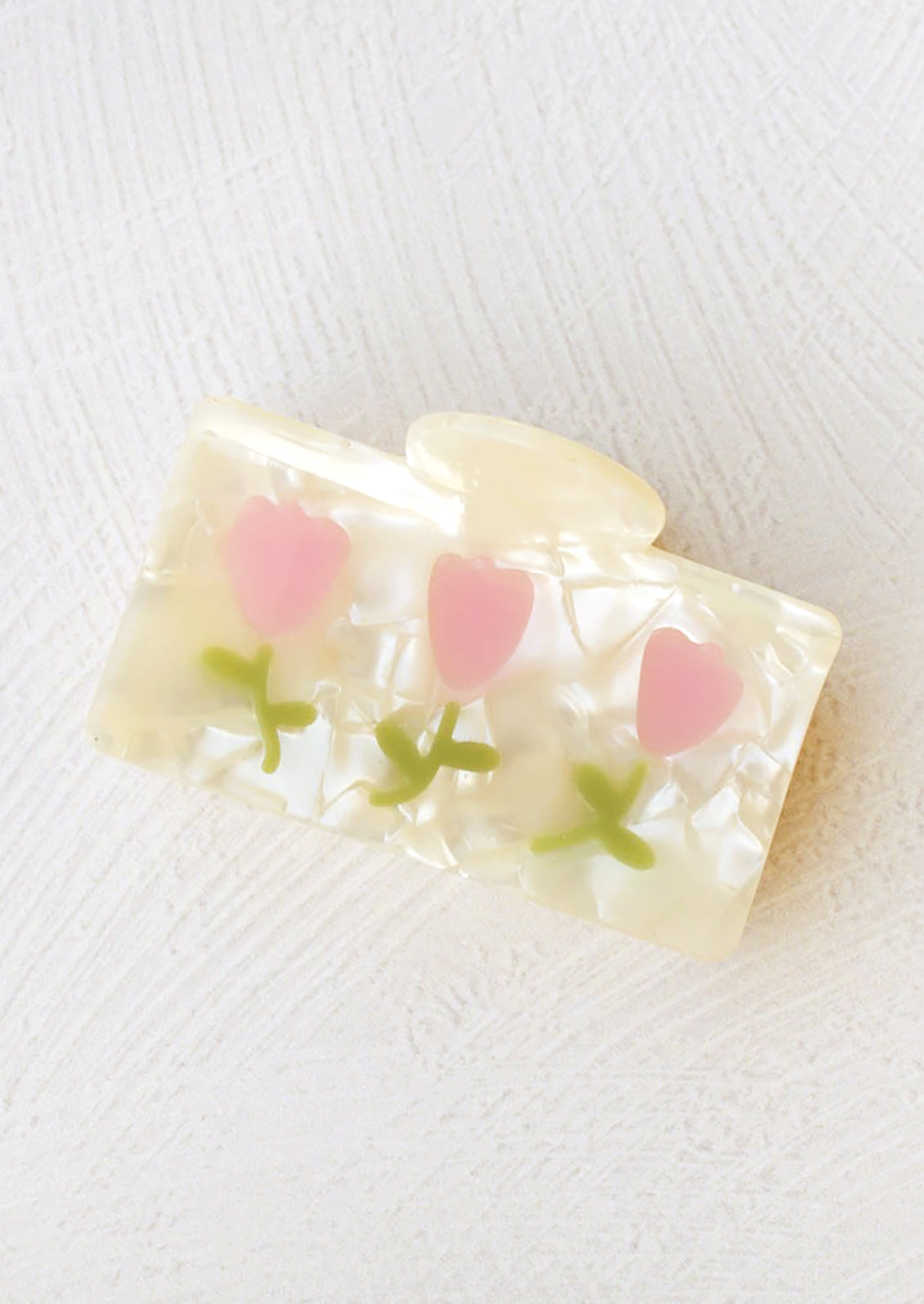 A rectangular hair claw with pearl finish with pink tulip design.
