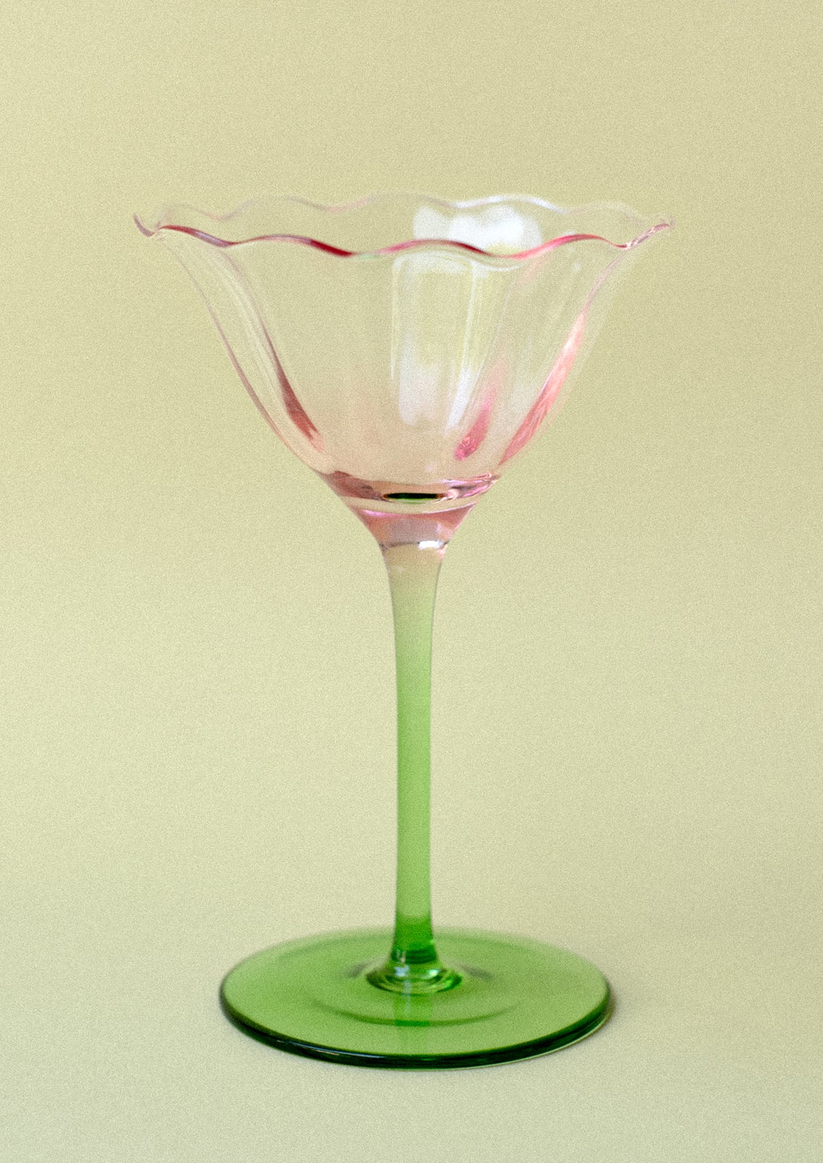 A coupe glass in shape of tulip with pink top and green bottom.