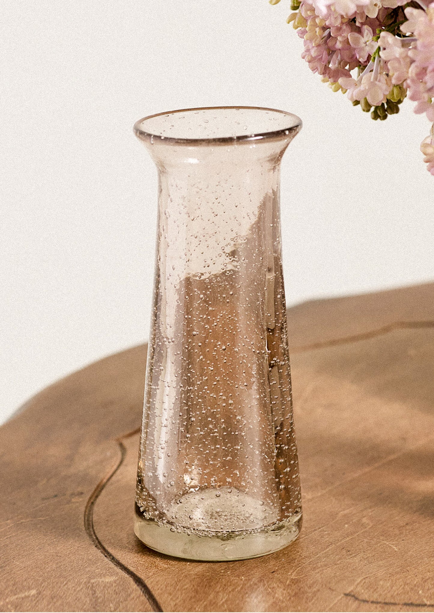 A glass bud vase in pink with bubble texture.