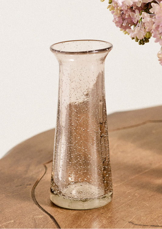 A glass bud vase in pink with bubble texture.