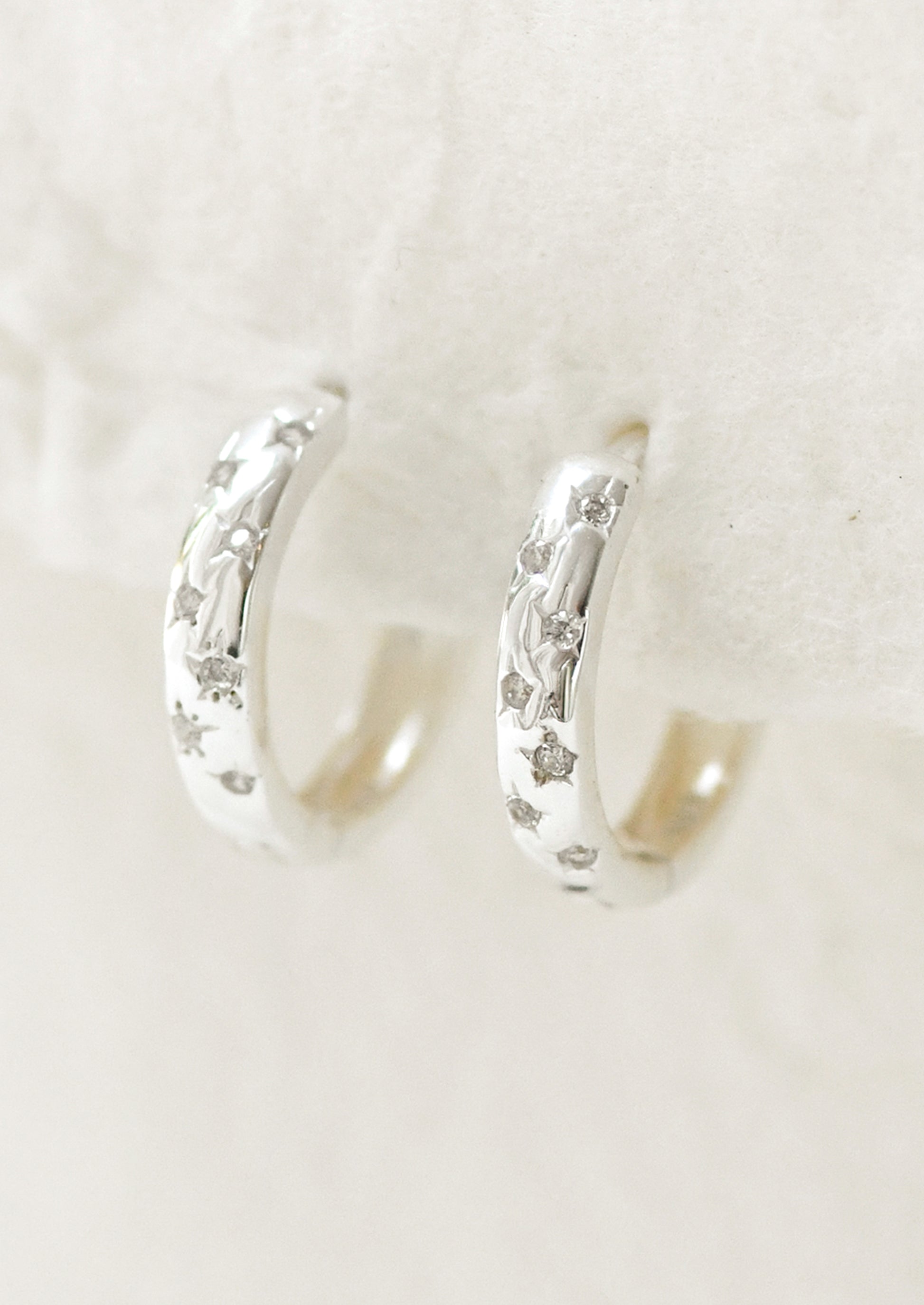 A pair of sterling silver hoop earrings with star gems.