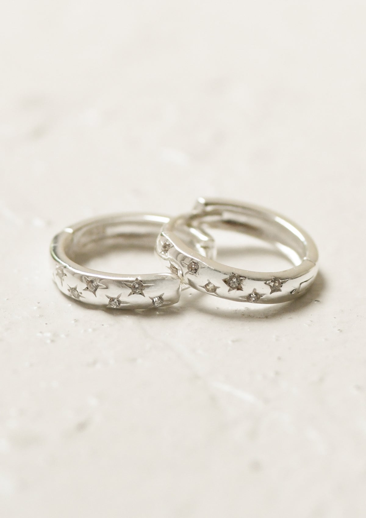 A pair of sterling silver hoop earrings with star gems.