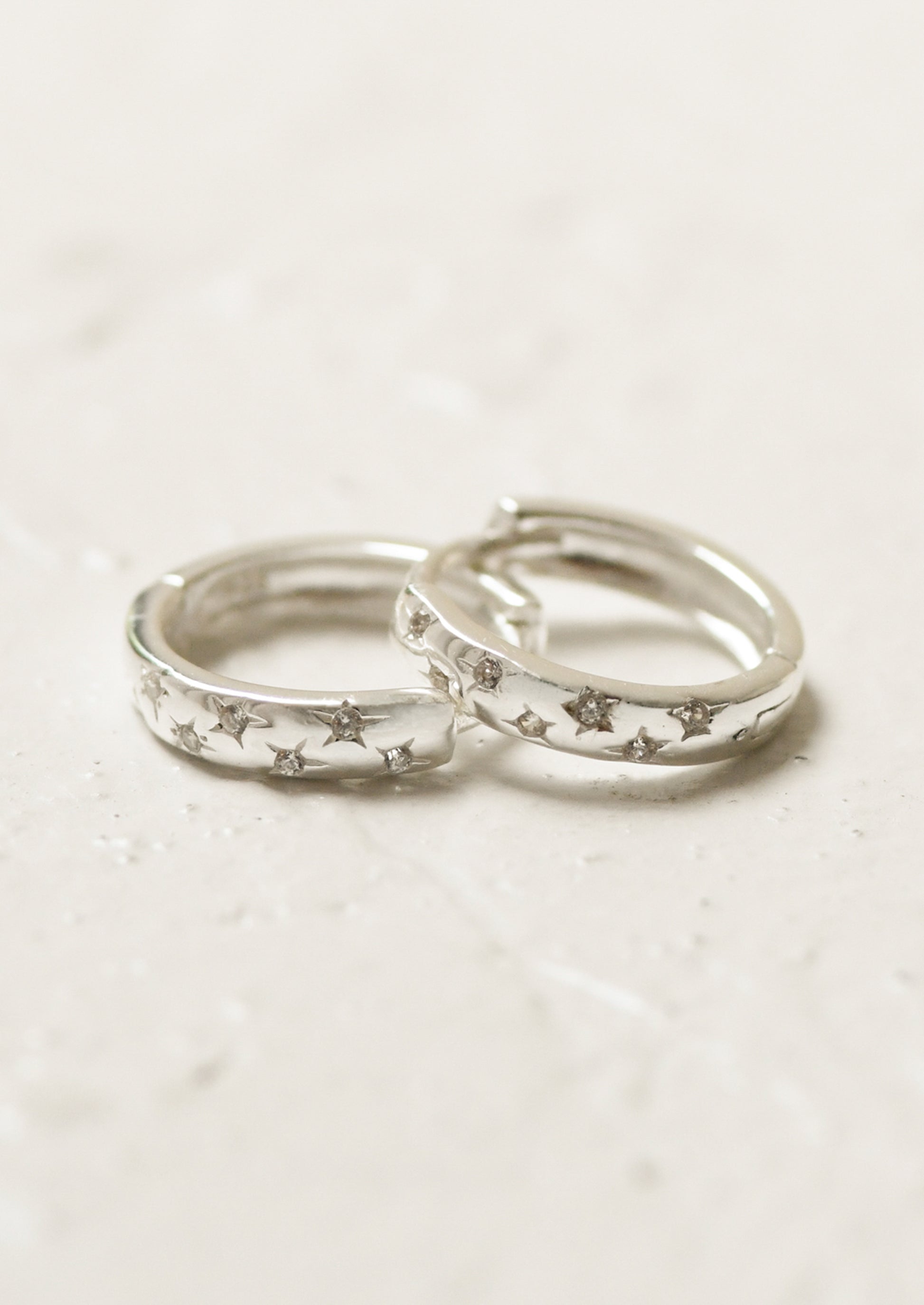 A pair of sterling silver hoop earrings with star gems.