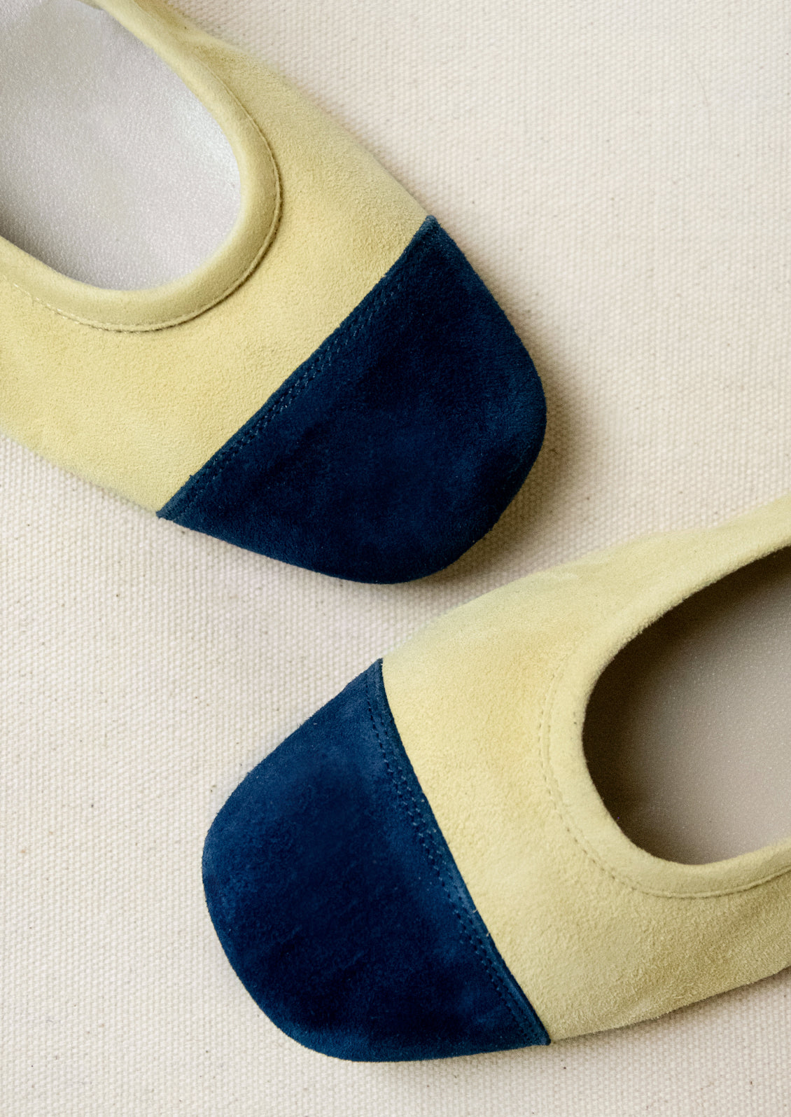 A pair of ballet flats in butter yellow with navy contrast.