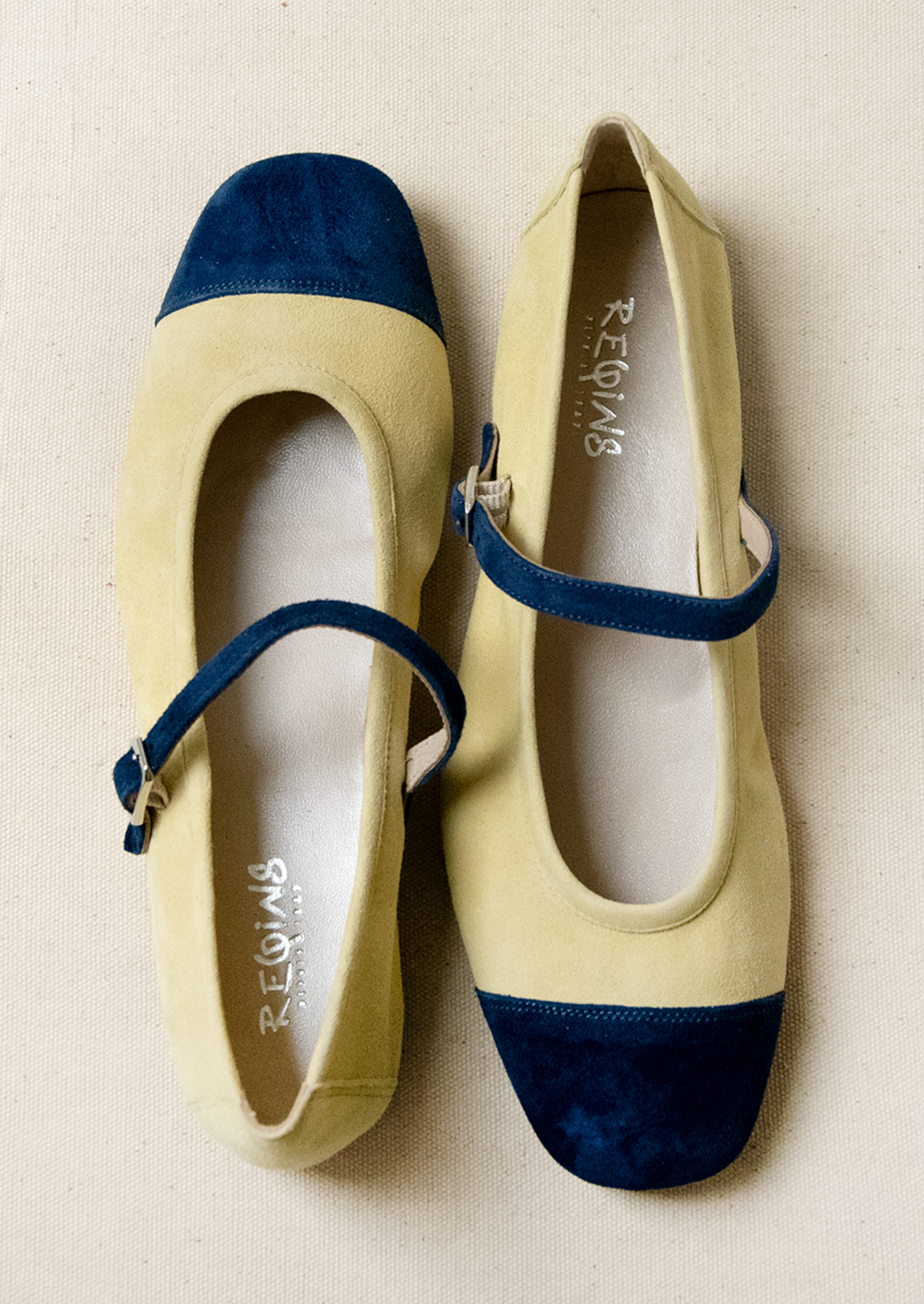 A pair of ballet flats in butter yellow with navy contrast.