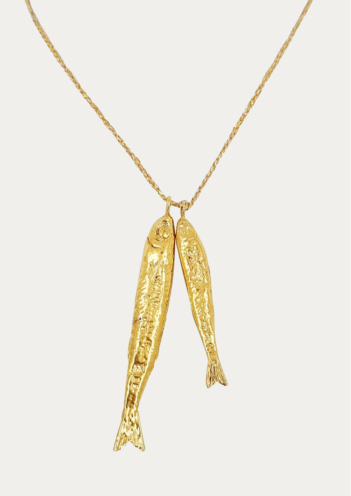 A necklace on gold string with two fish charms.