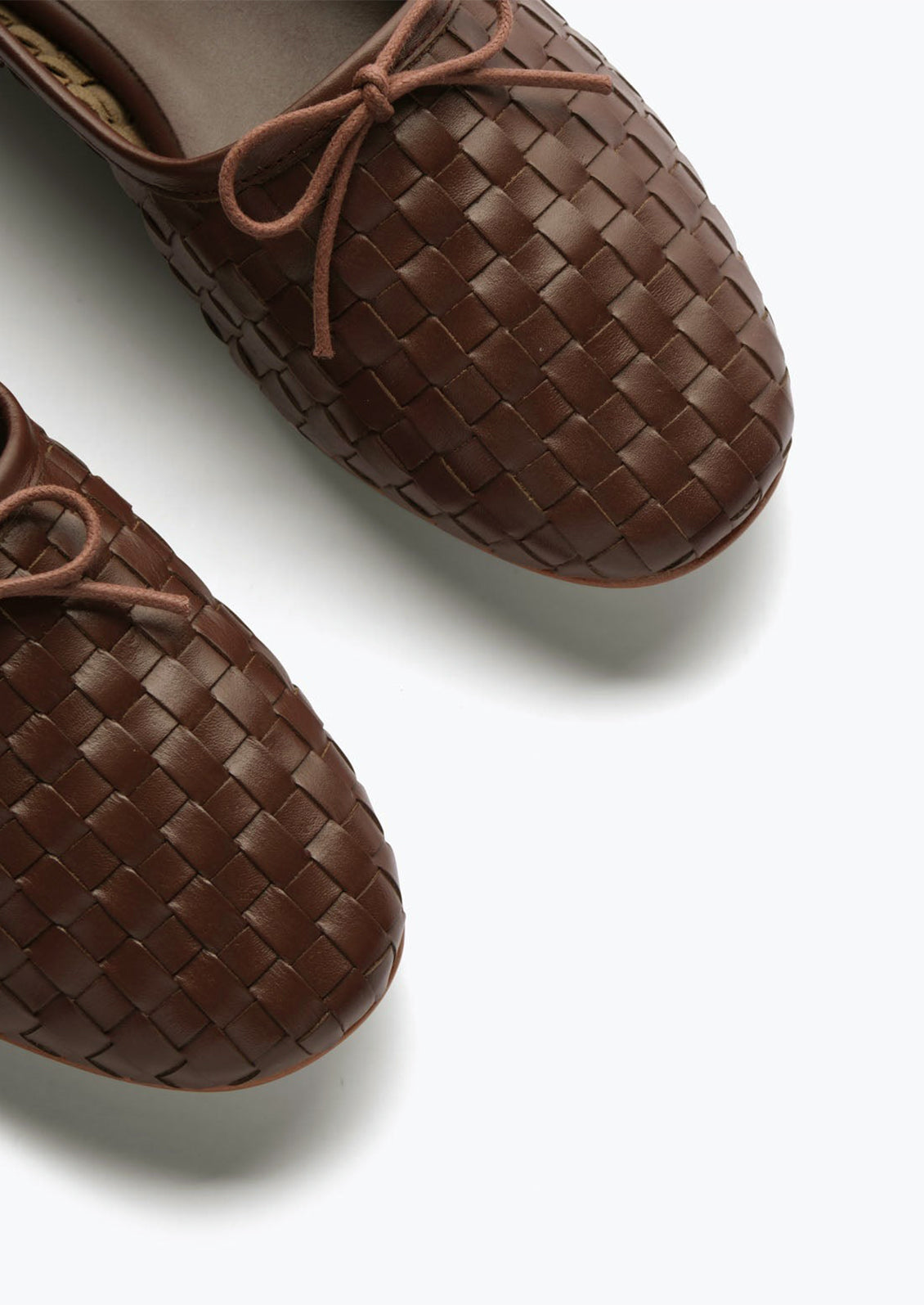 Dark brown woven leather ballet flats with bow detail.