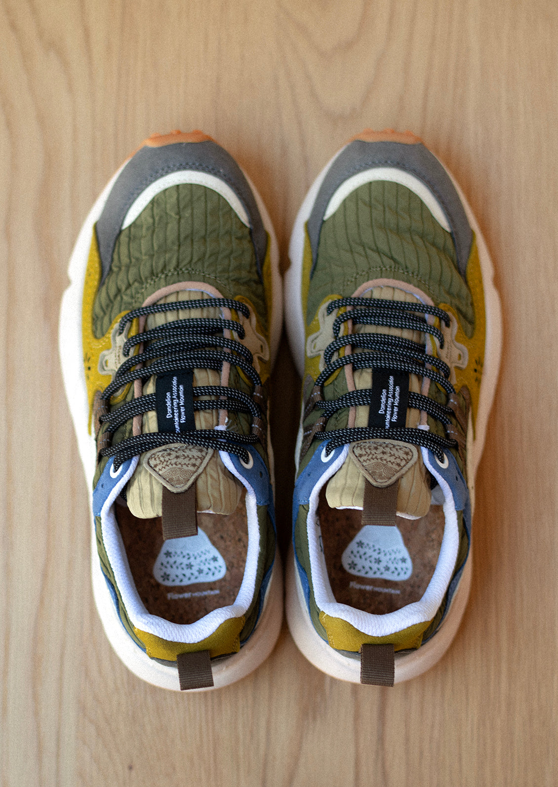 A pair of sneakers in ribbed nylon and suede, green and mustard color palette.