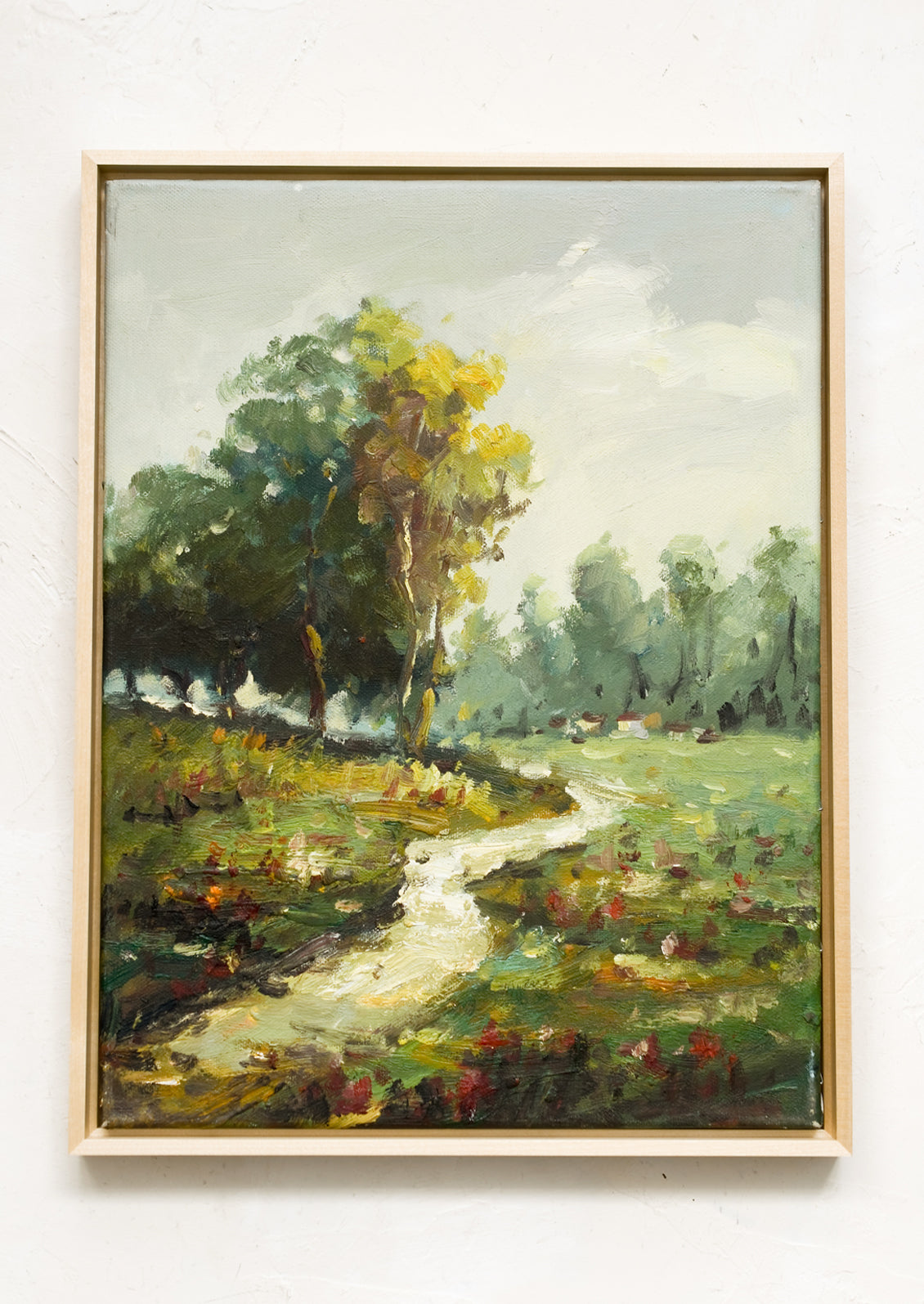 A framed landscape oil painting of a path running through a flowery meadow.