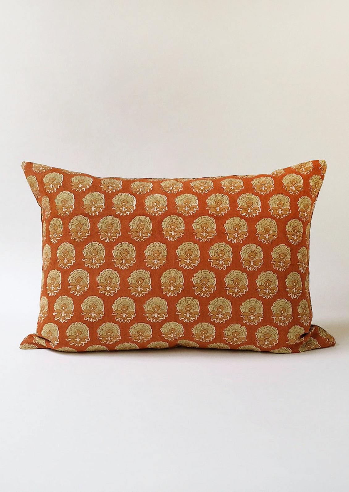 A rust and mossy green floral block print pillow.