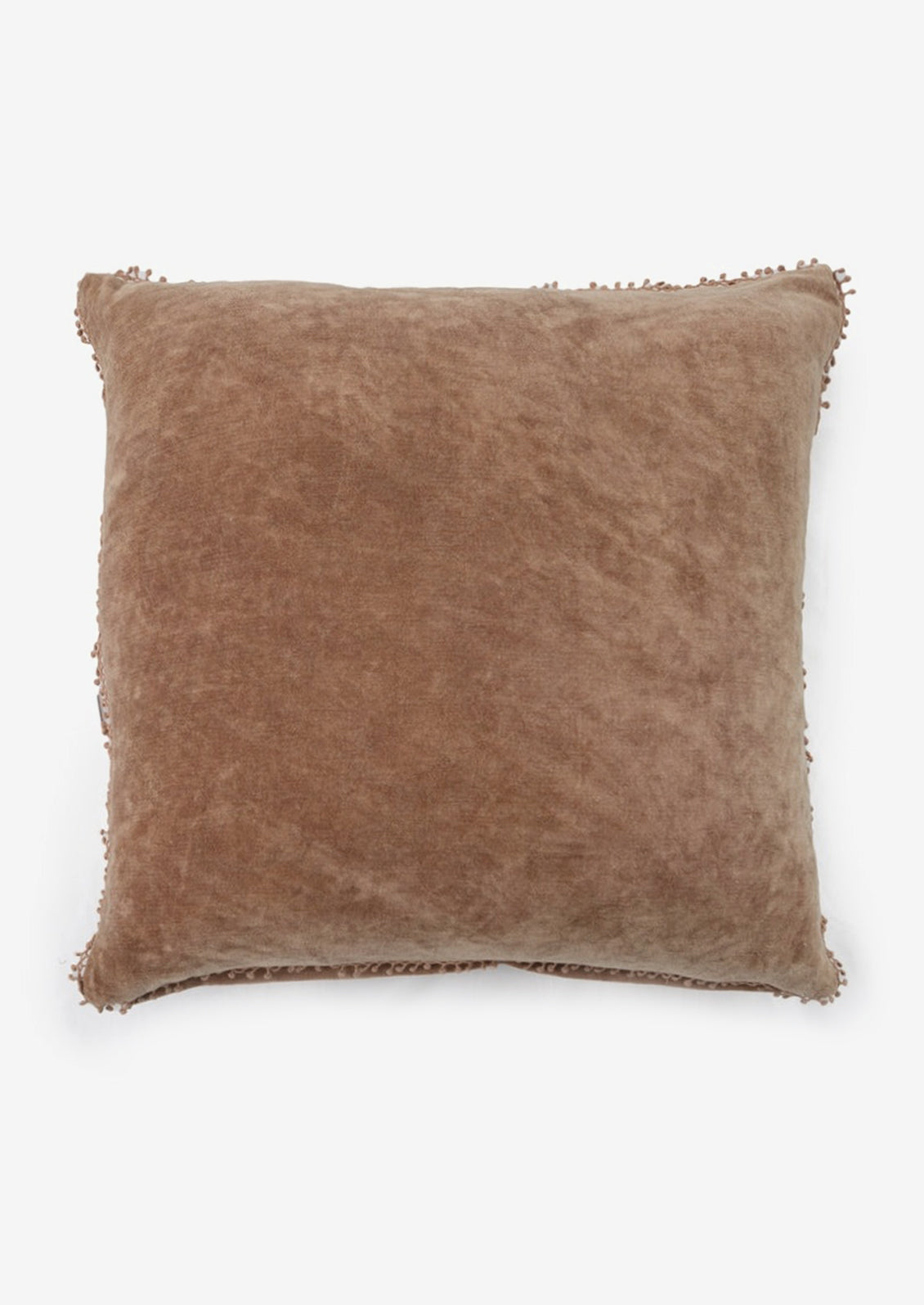 A velvet throw pillow with pom pom trim in fawn color.