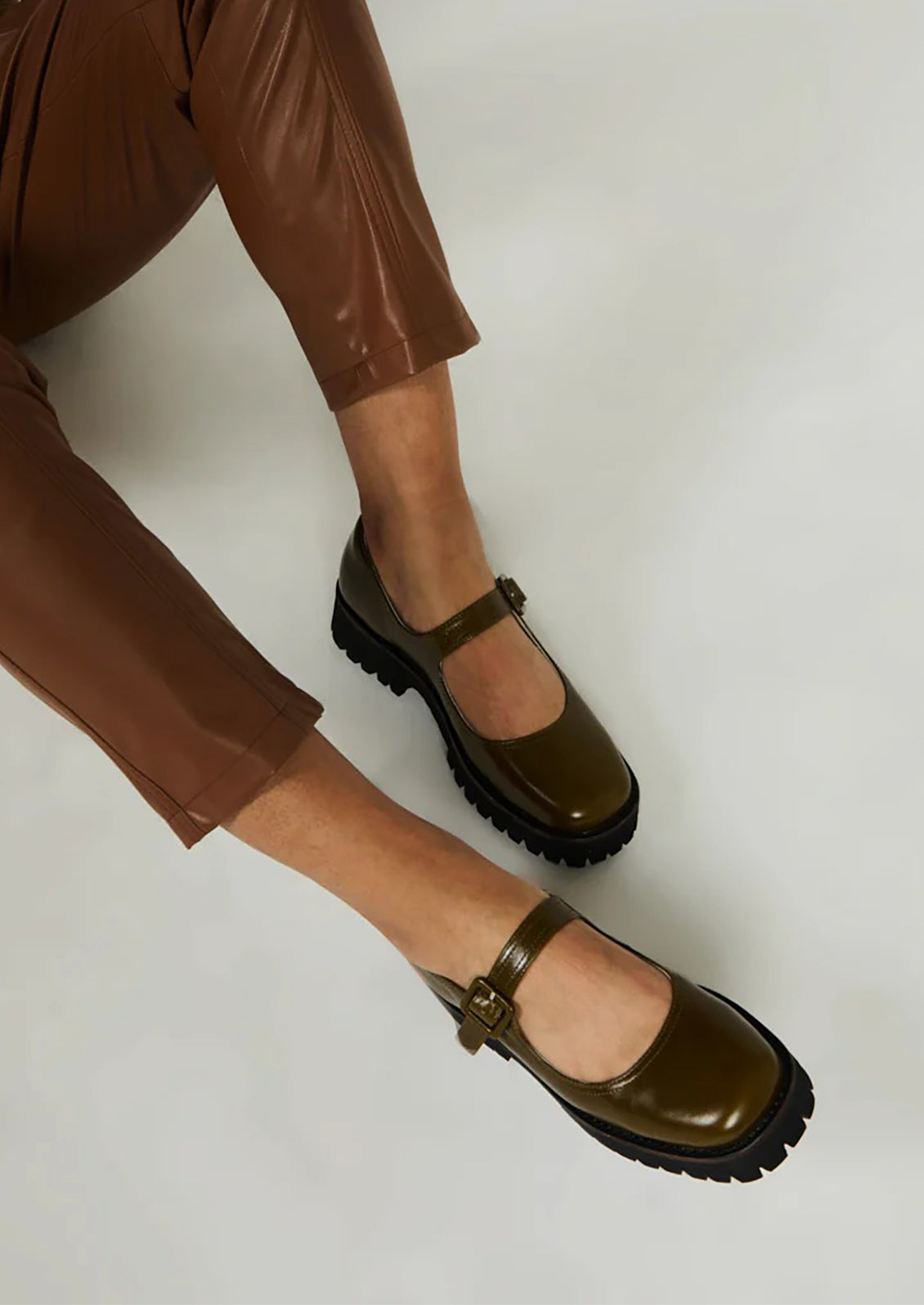 A pair of mary jane shoes in olive green with chunky lug sole.