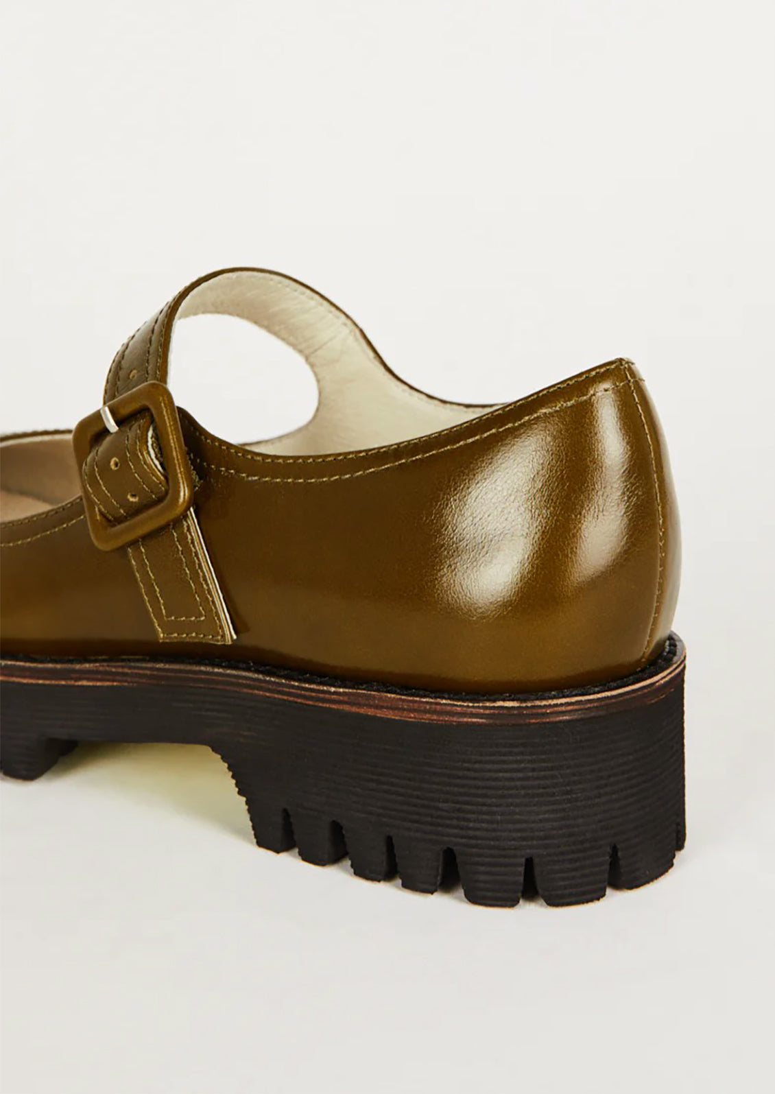 A pair of mary jane shoes in olive green with chunky lug sole.